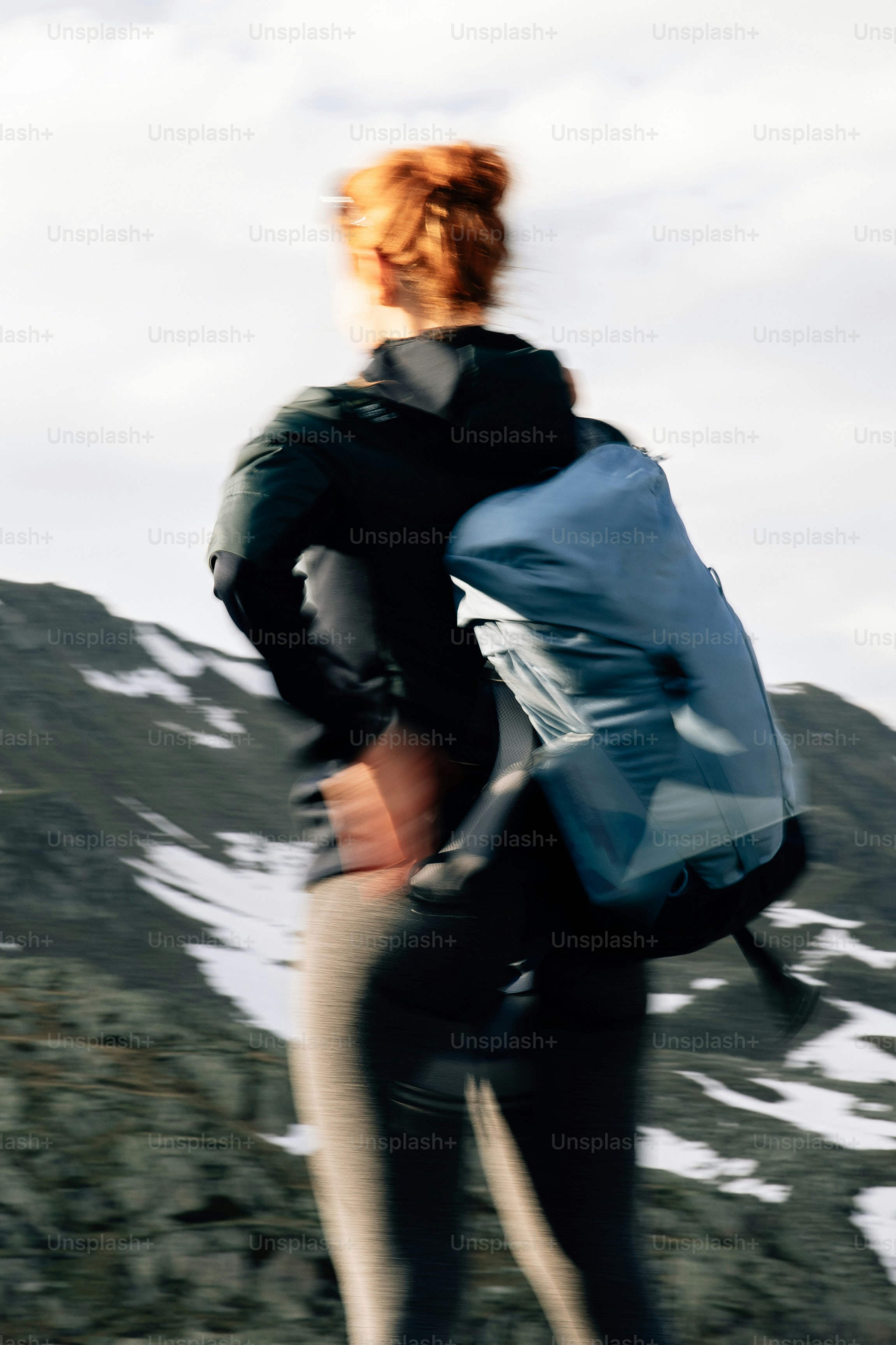 A person with a blue backpack hiking in snowy mountains.