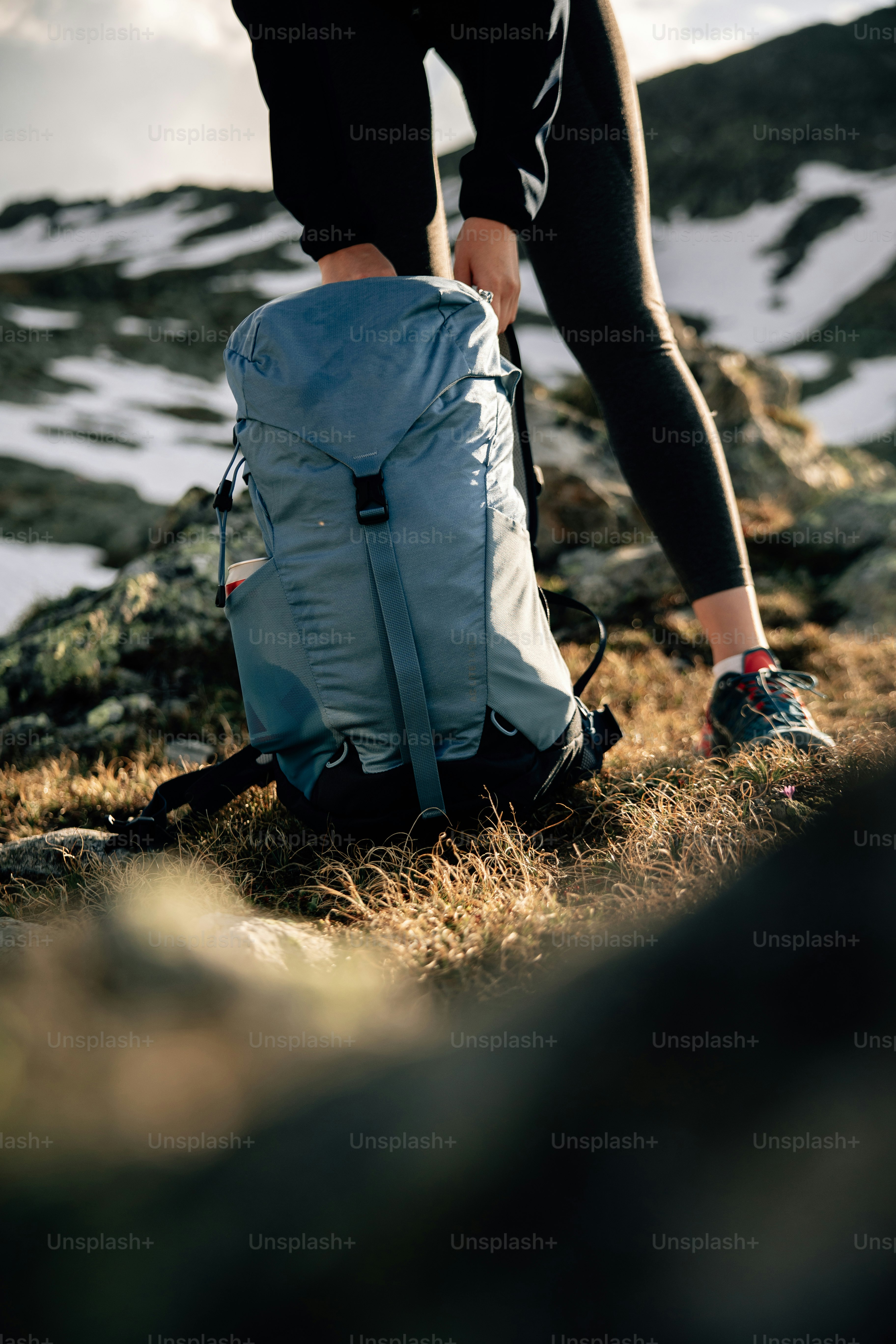 Seseorang menyesuaikan ransel biru di gunung bersalju.