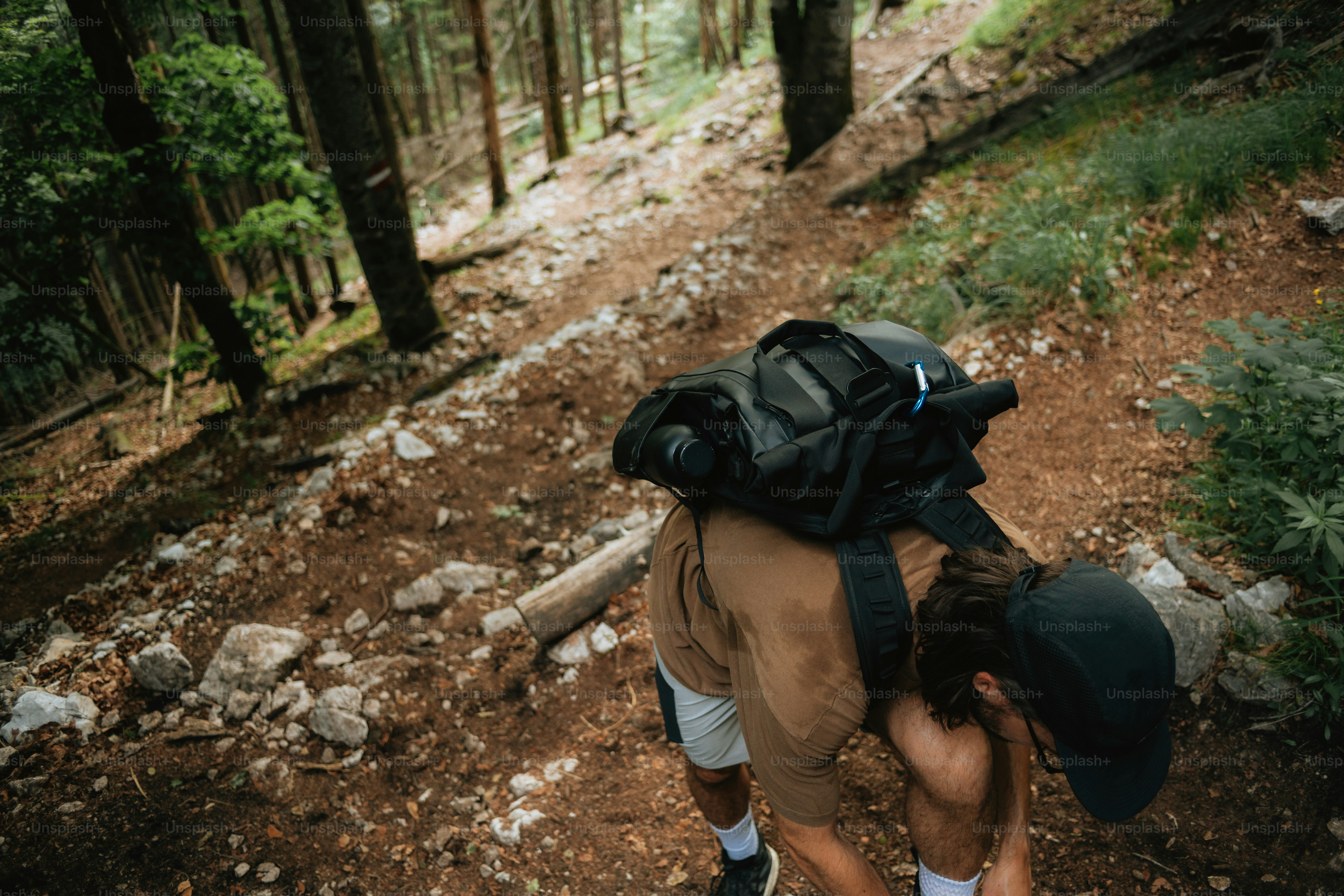 Pendaki dengan ransel mendaki jalur hutan yang curam.