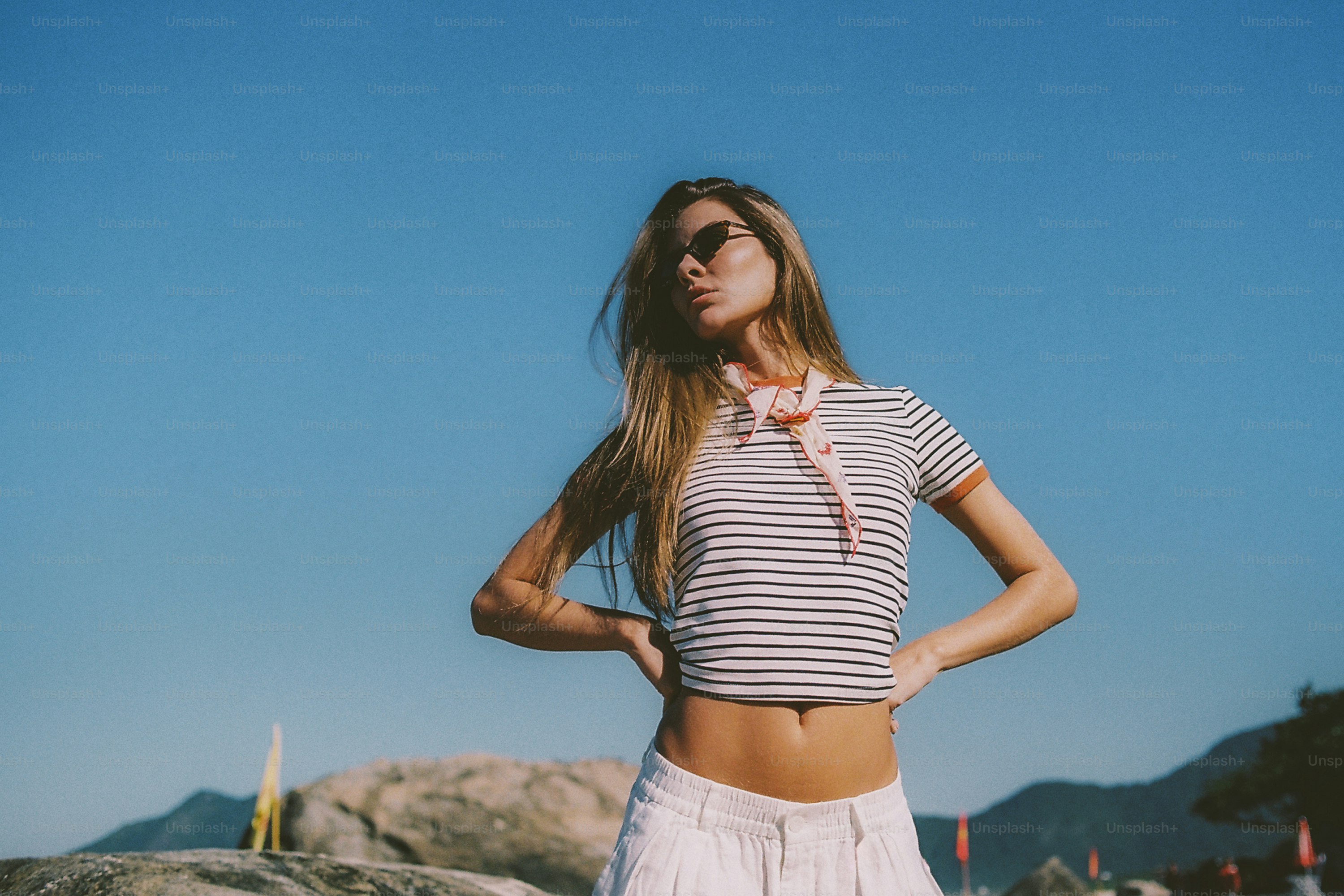 Woman in striped shirt and sunglasses posing outdoors.