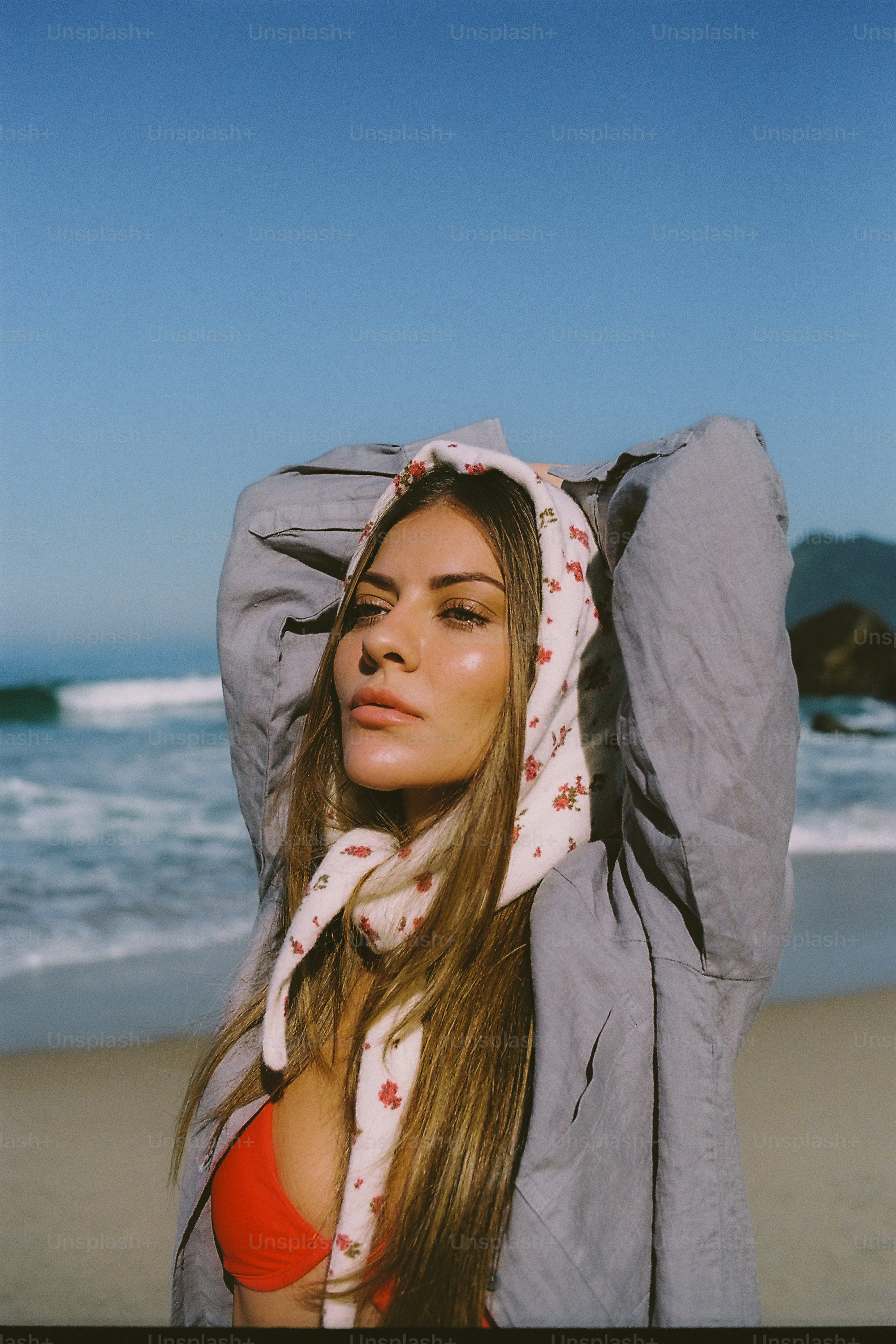 Woman with headscarf and orange bikini on a sunny beach.