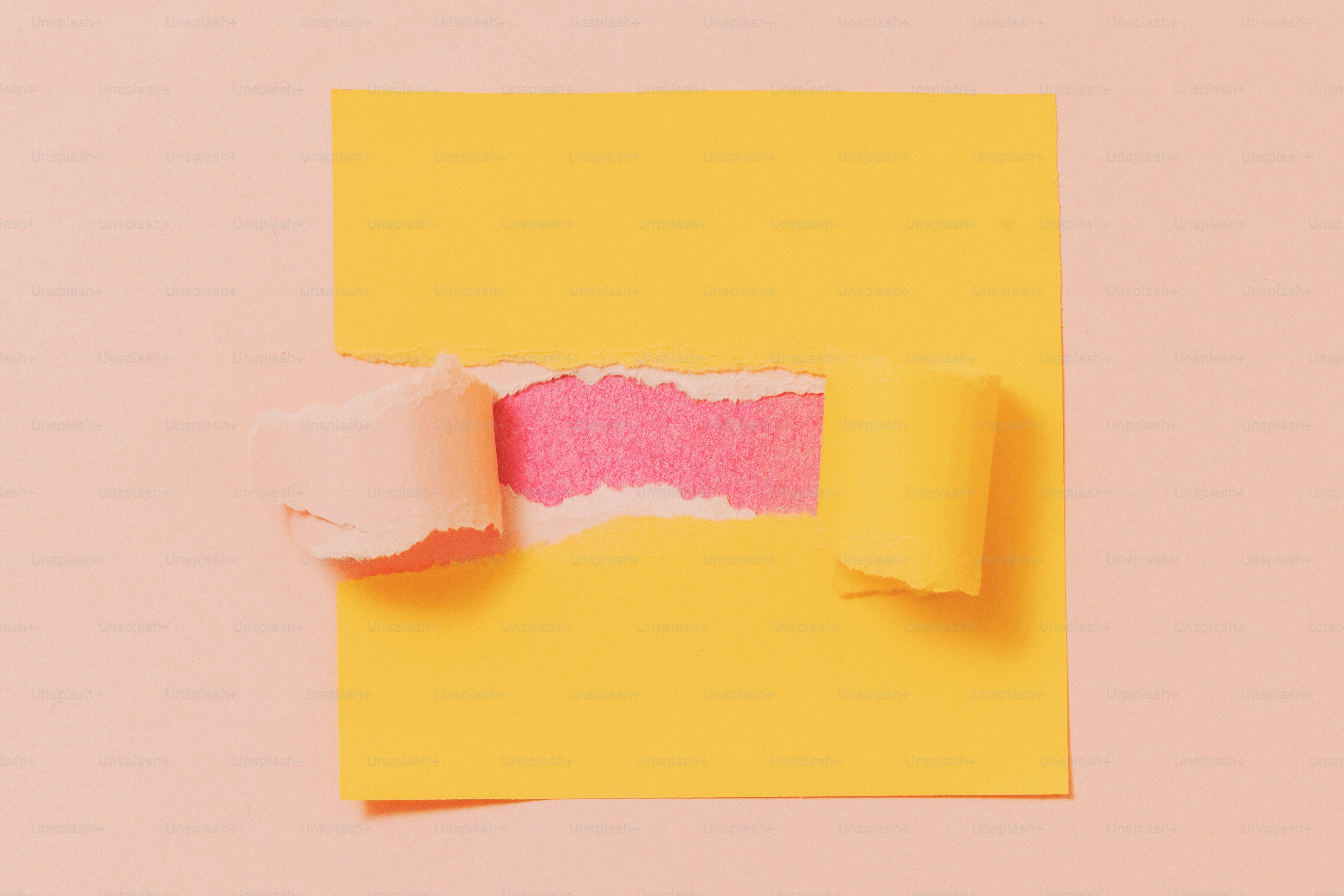 Carta gialla strappata orizzontalmente rivelando uno sfondo rosa vibrante