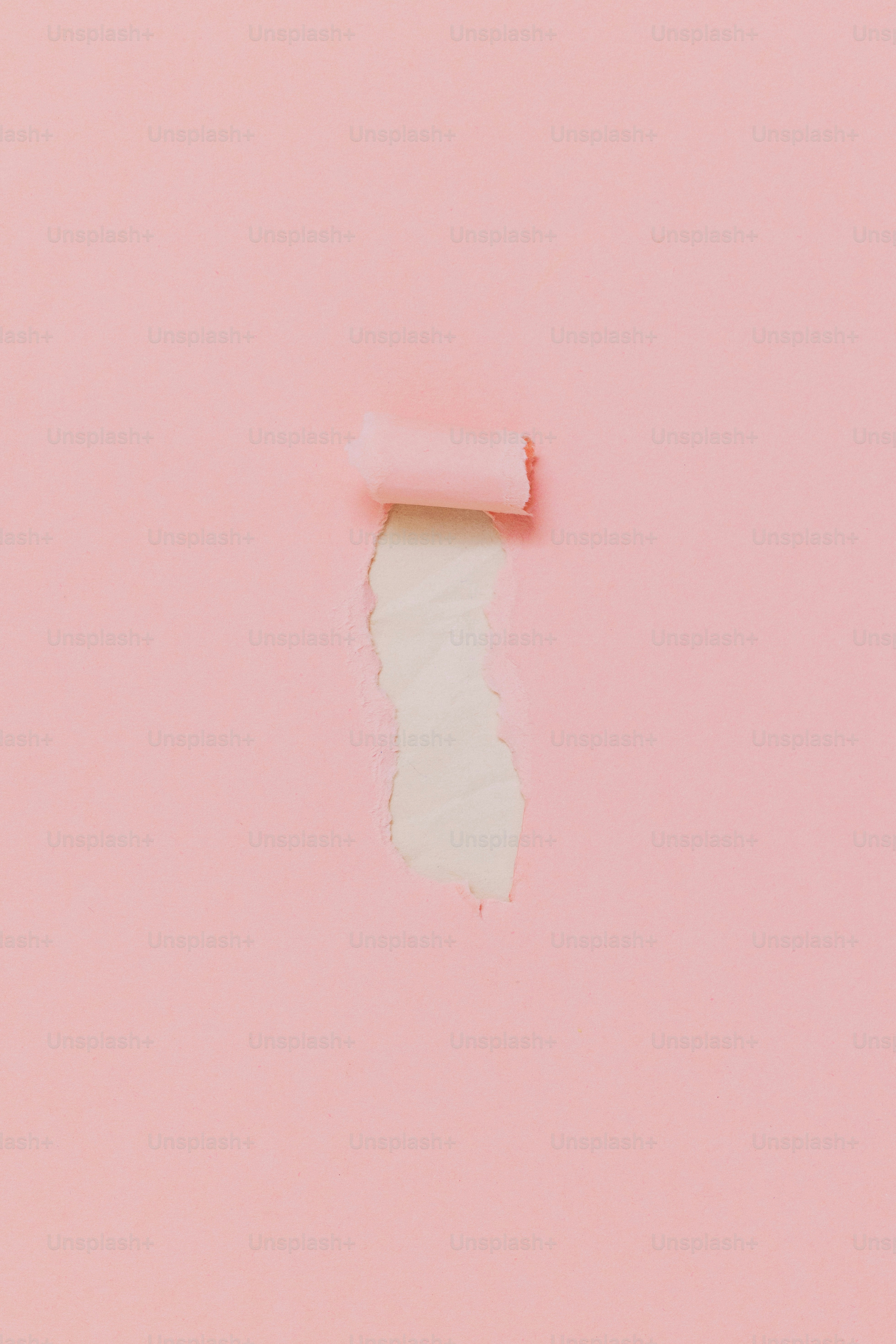 Ein zerrissenes rosa Papier, das eine hellere Farbe darunter enthüllte.