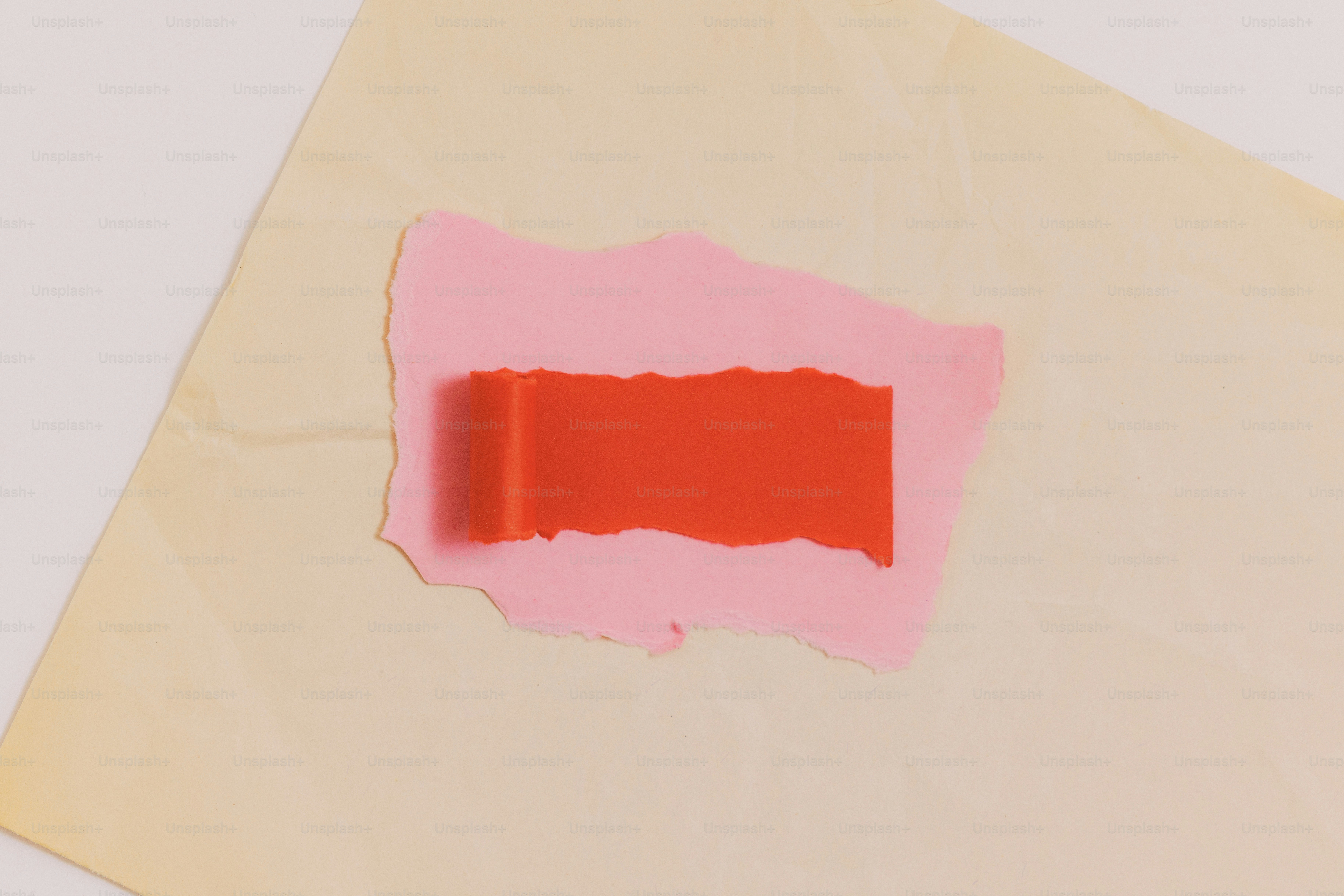 Torn pink paper revealing a vibrant red rectangle on beige.