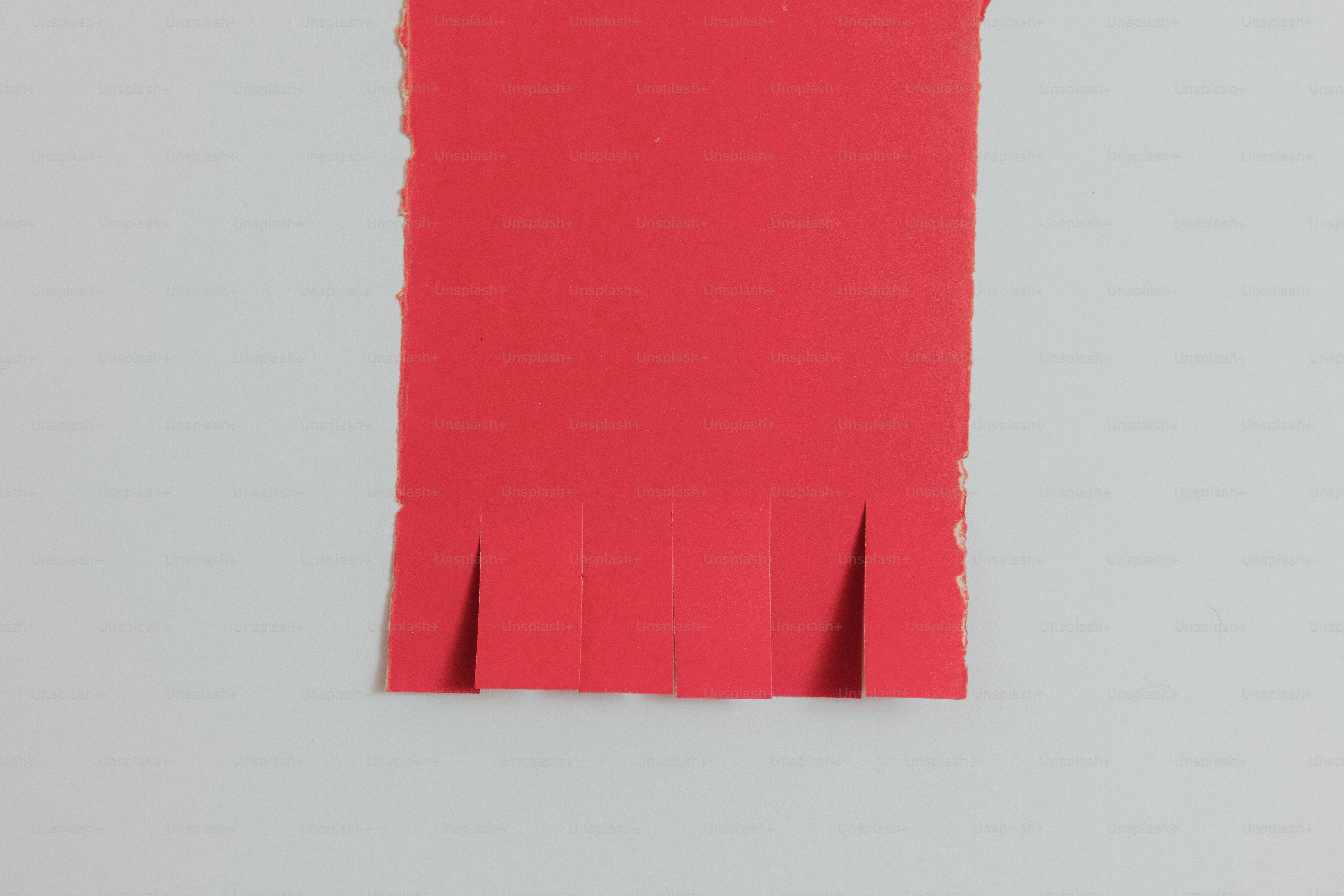Red paper with fringed bottom edge on gray background.