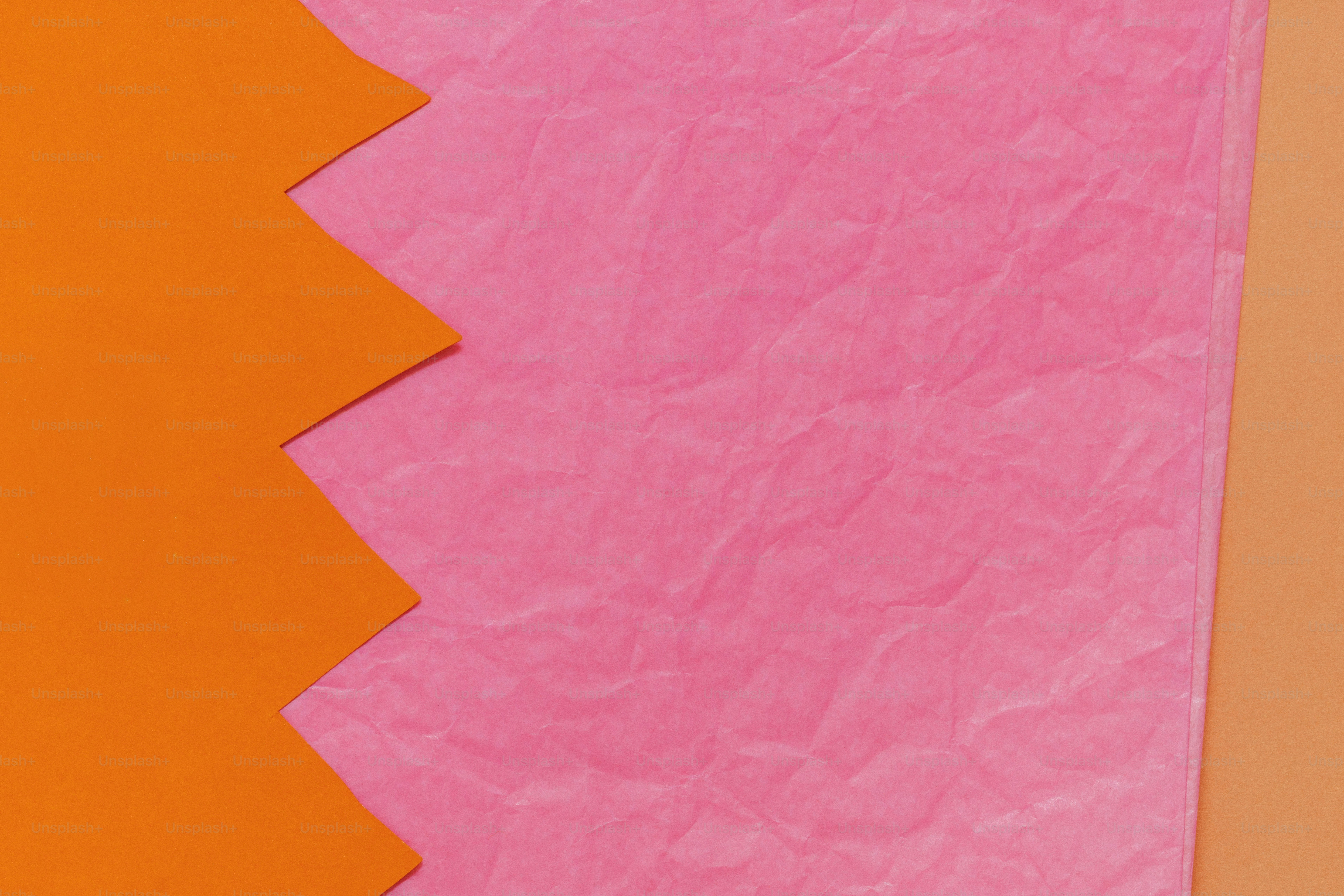 Pink crumpled paper with jagged orange and peach borders.