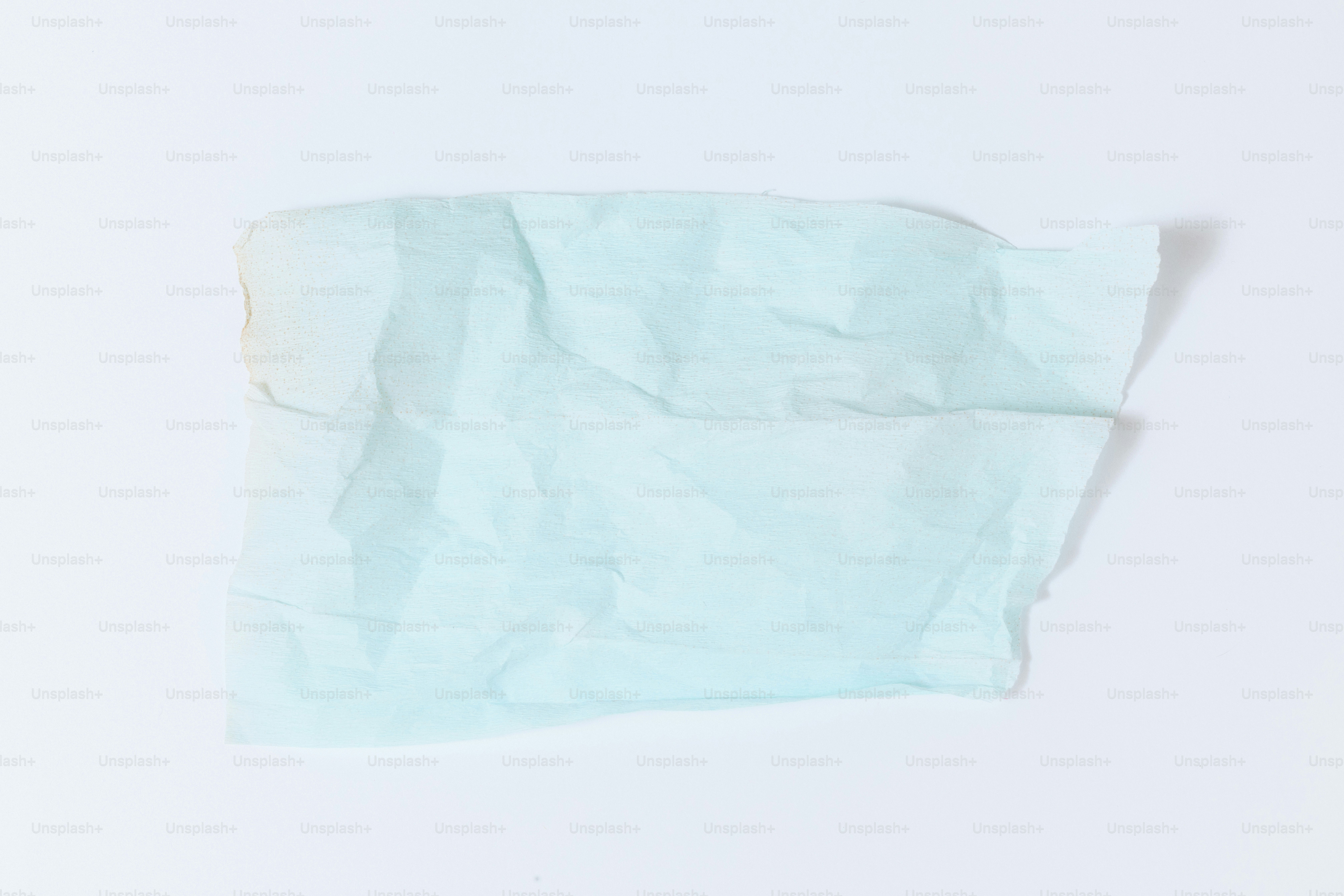 A crumpled piece of light blue tissue paper on white.