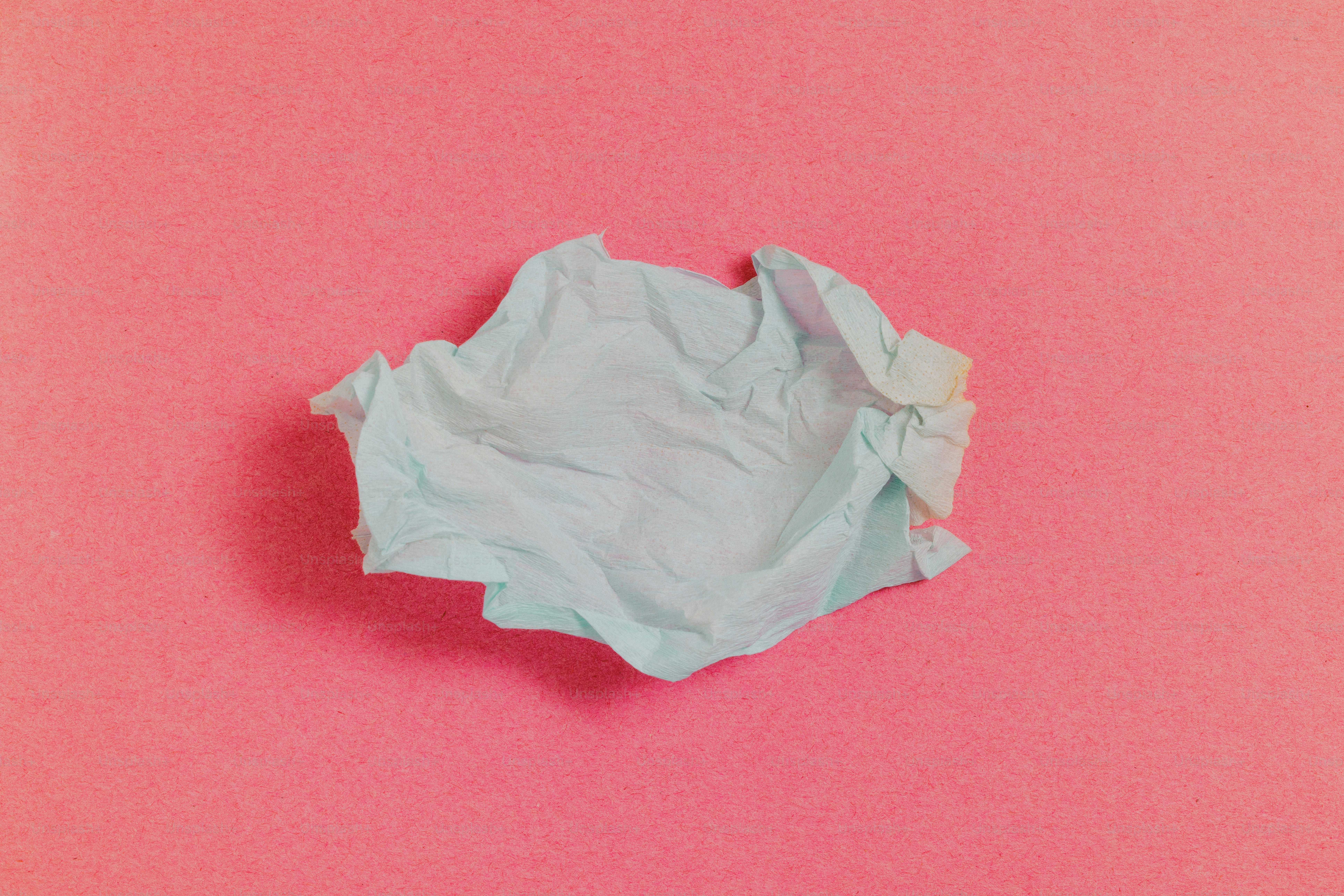 Un foglio azzurro chiaro accartocciato su uno sfondo rosa vibrante
