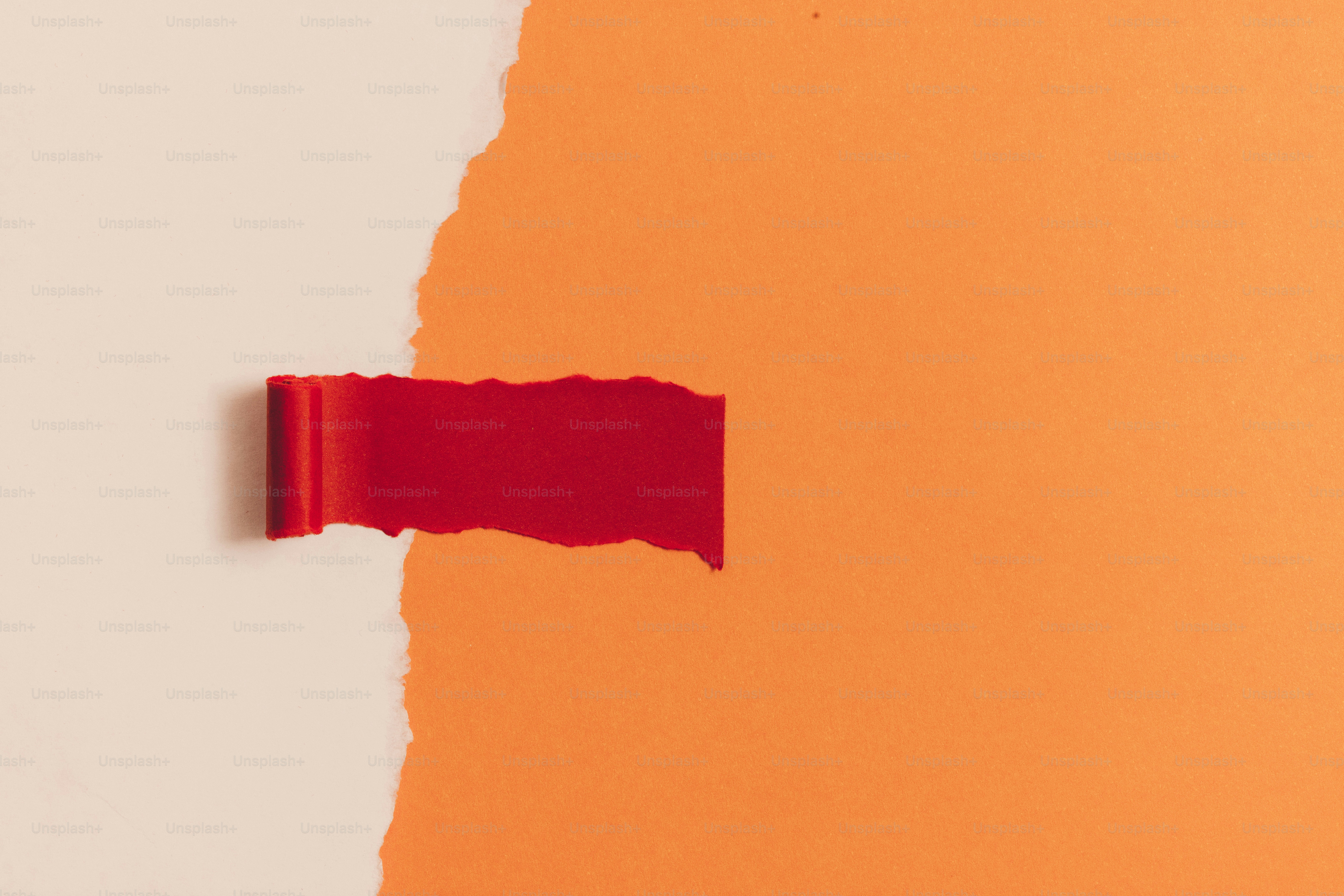 Carta strappata rossa che rivela uno sfondo arancione