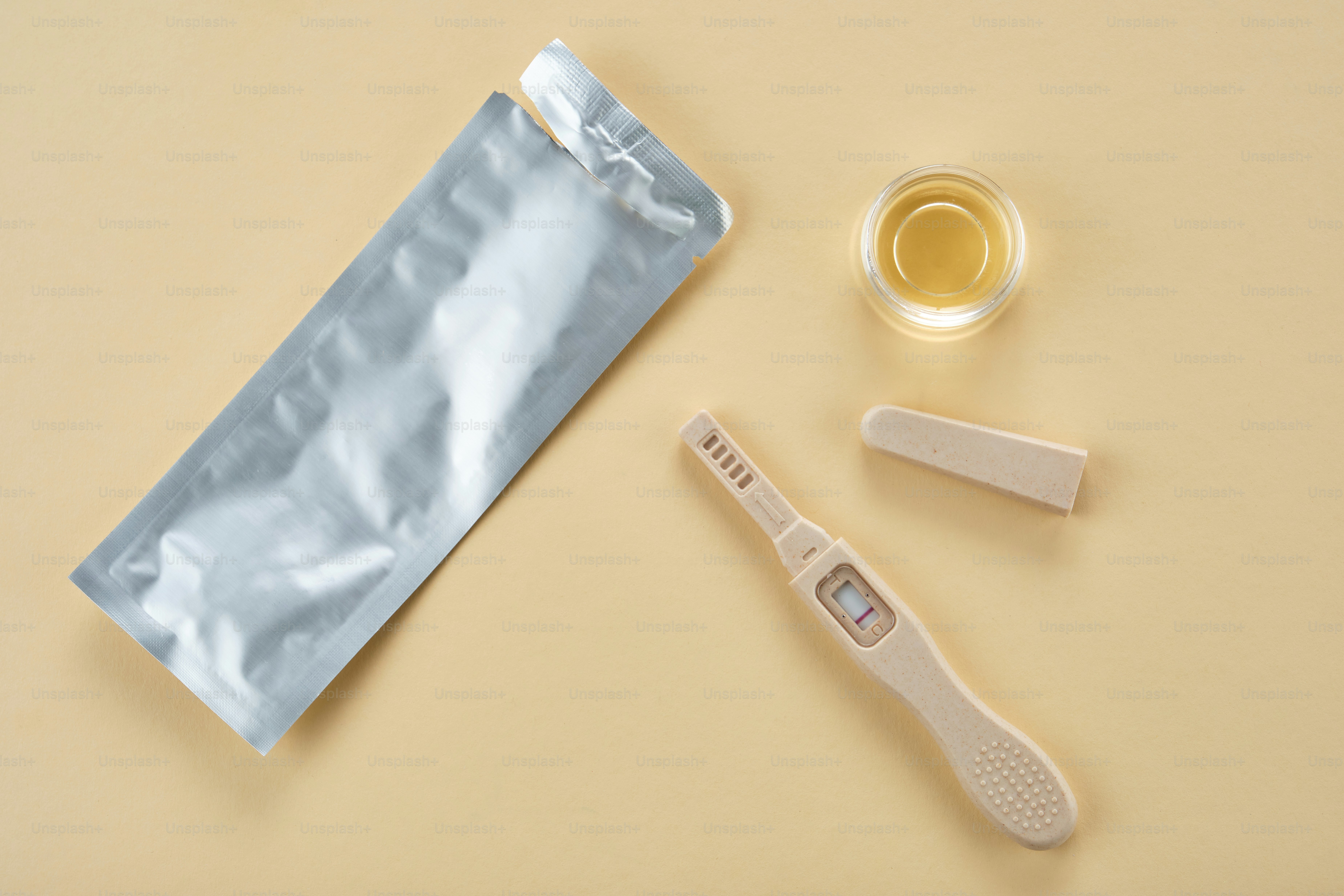 Kit de test de grossesse avec un échantillon d’urine sur fond beige.