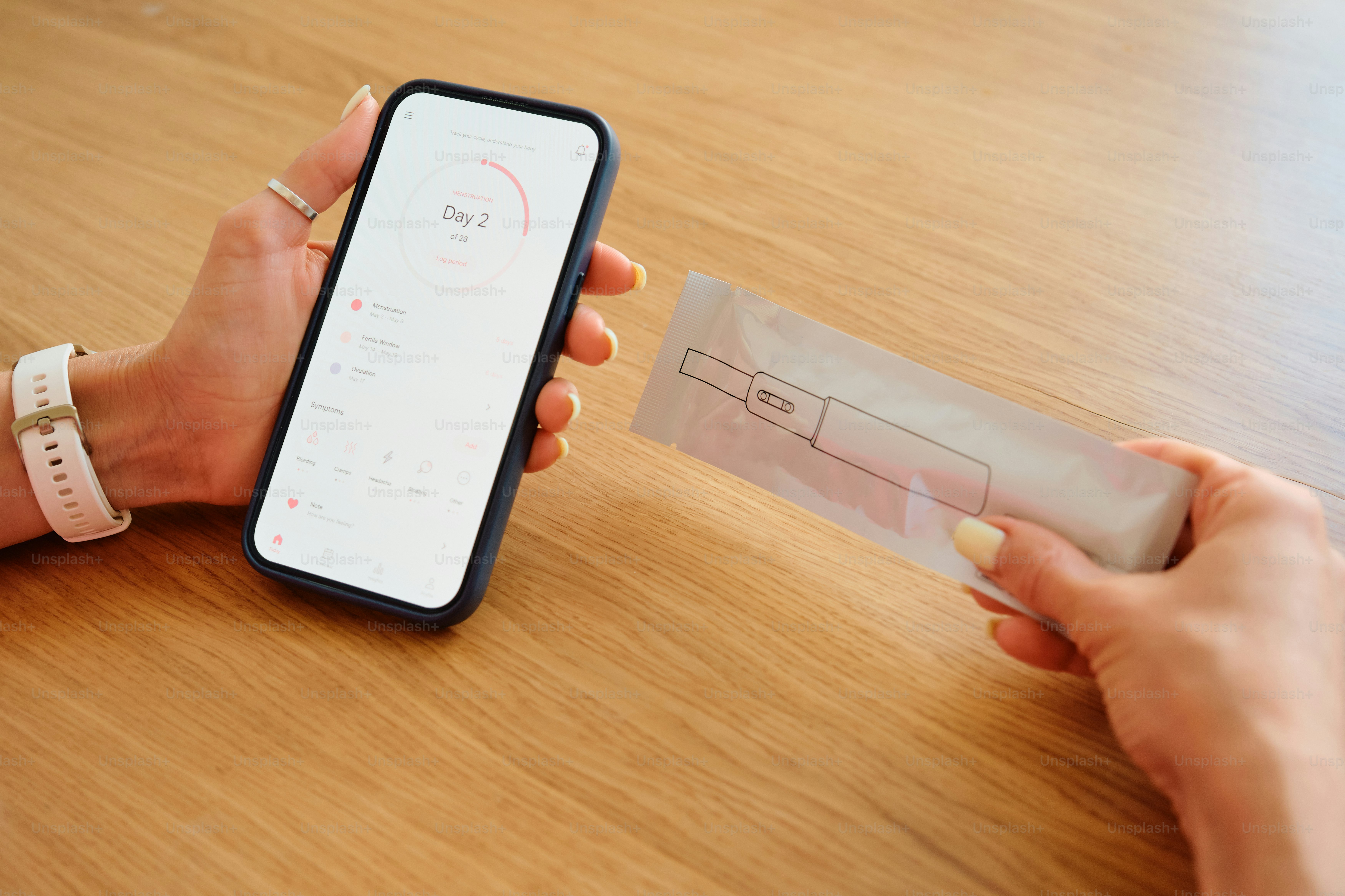 Mains tenant le téléphone affichant une application et un kit de test médical.