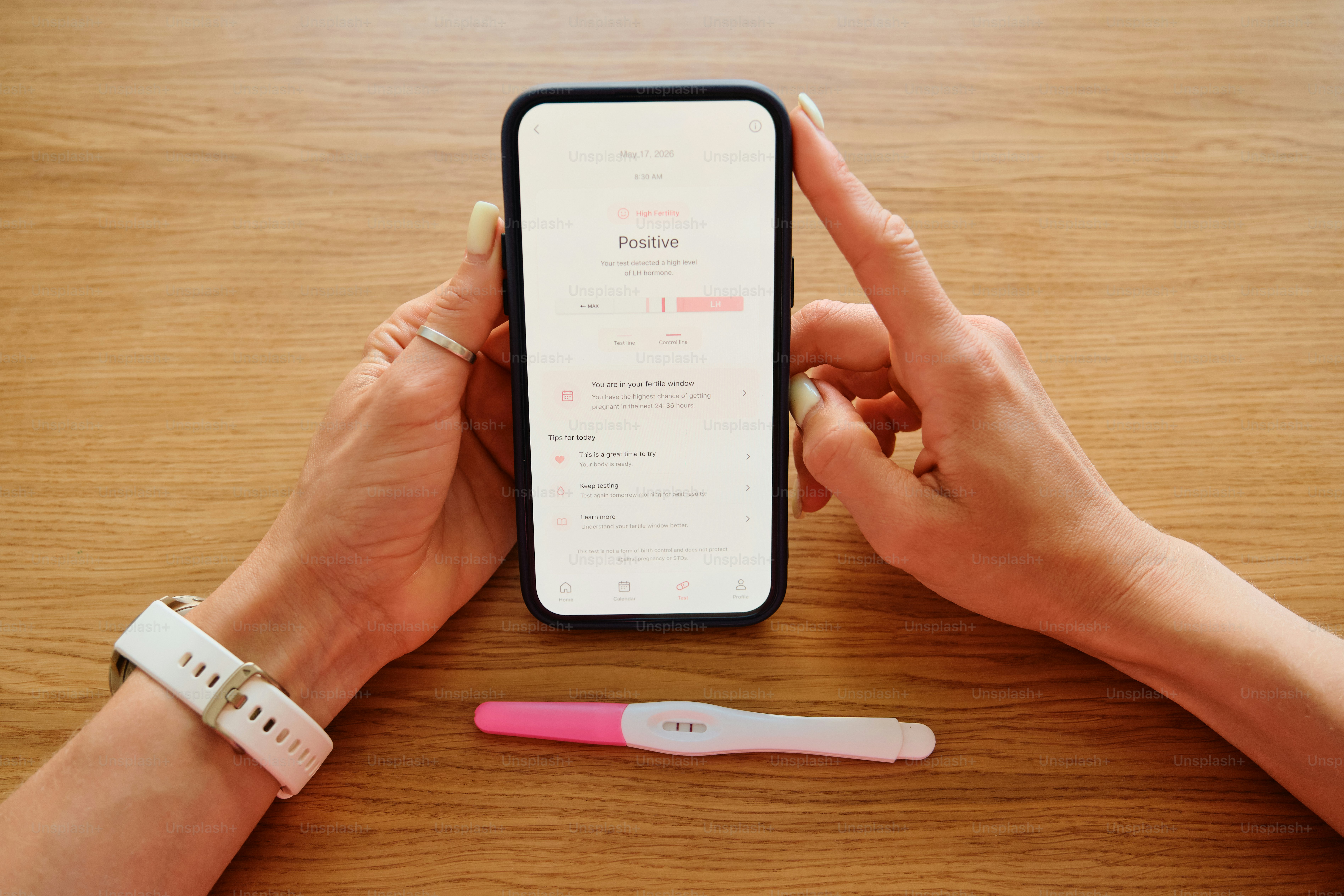 Test de grossesse et smartphone en main sur une table en bois.