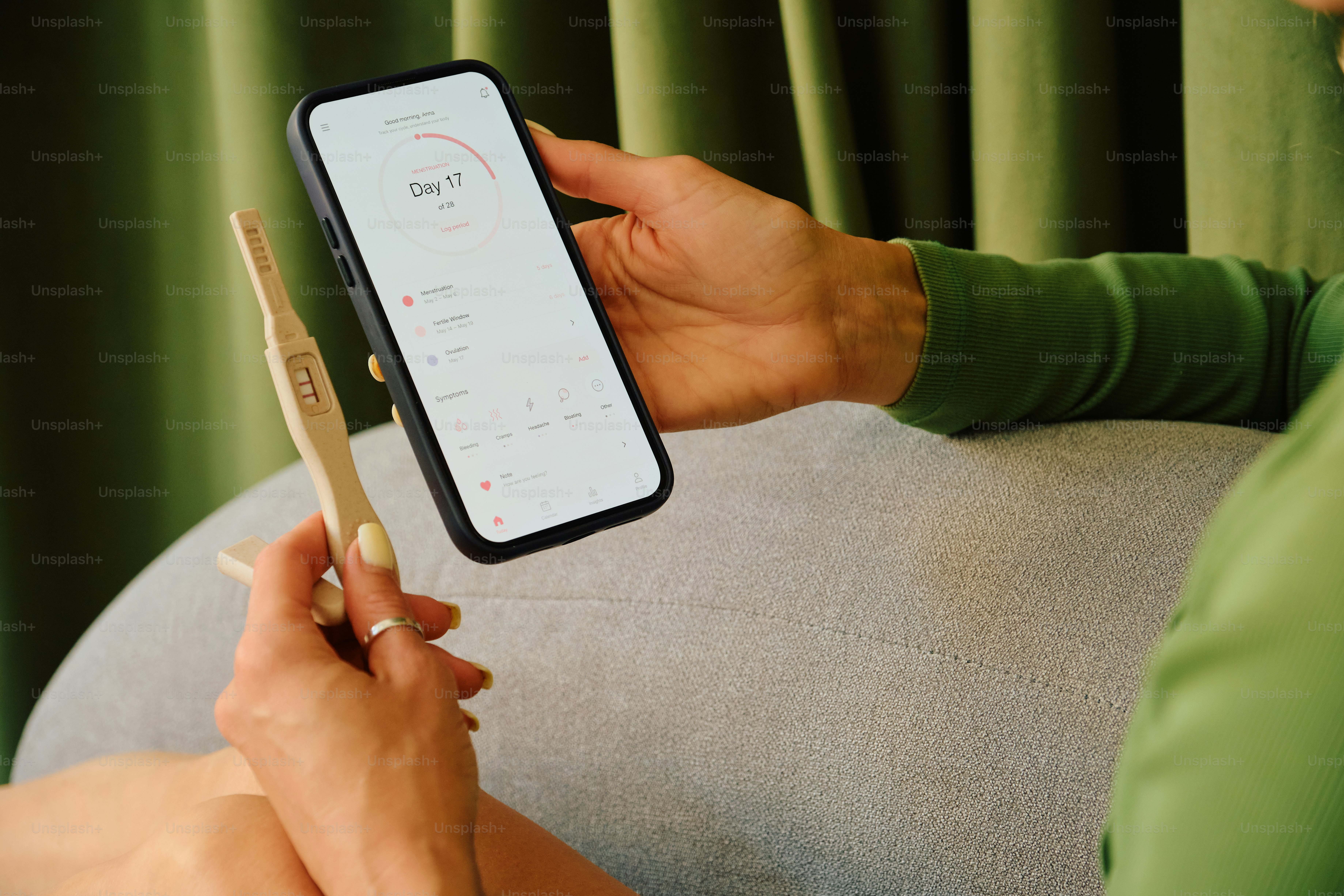 Personne tenant un smartphone et un test de grossesse.