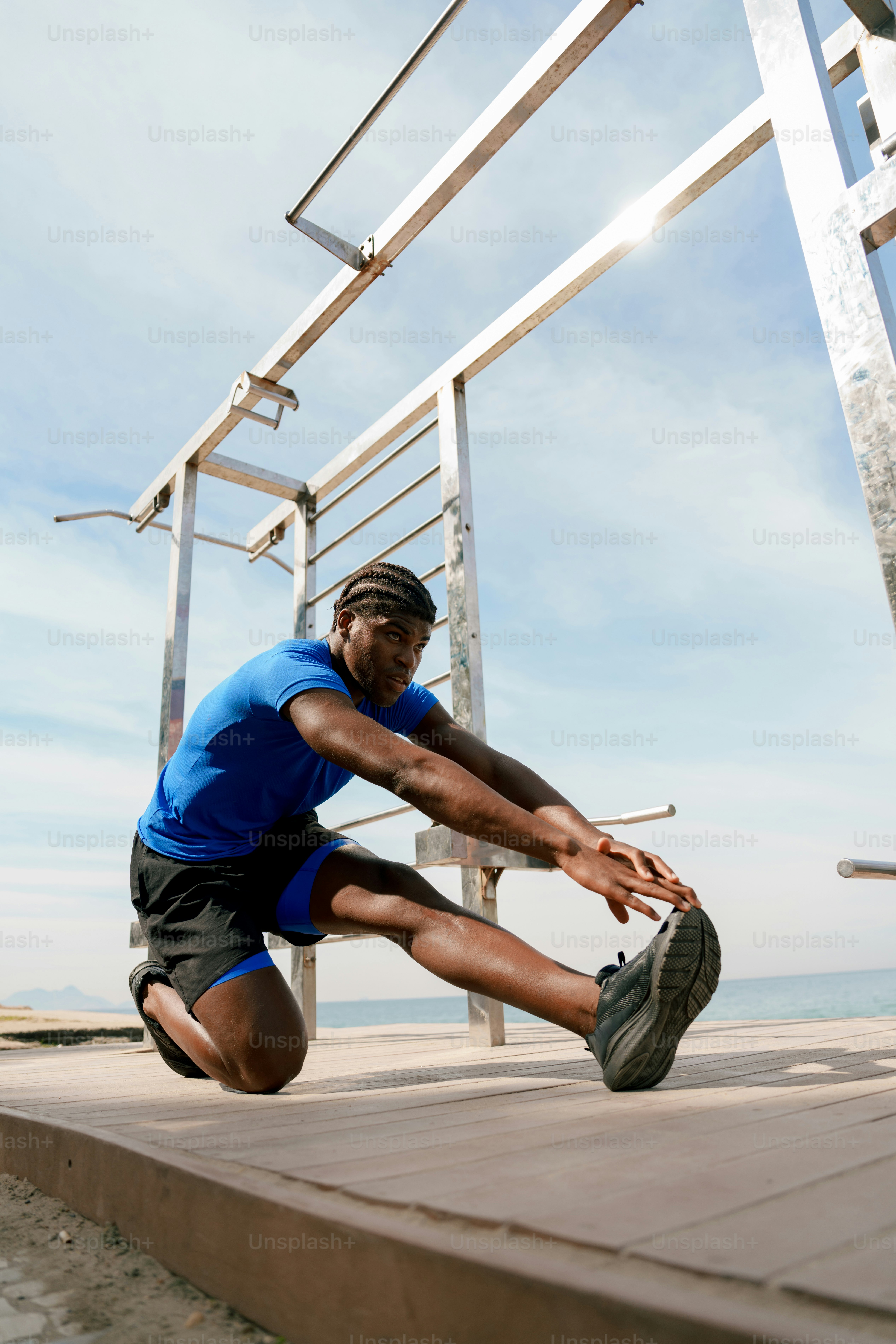 A man stretching his leg on an outdoor wooden platform.