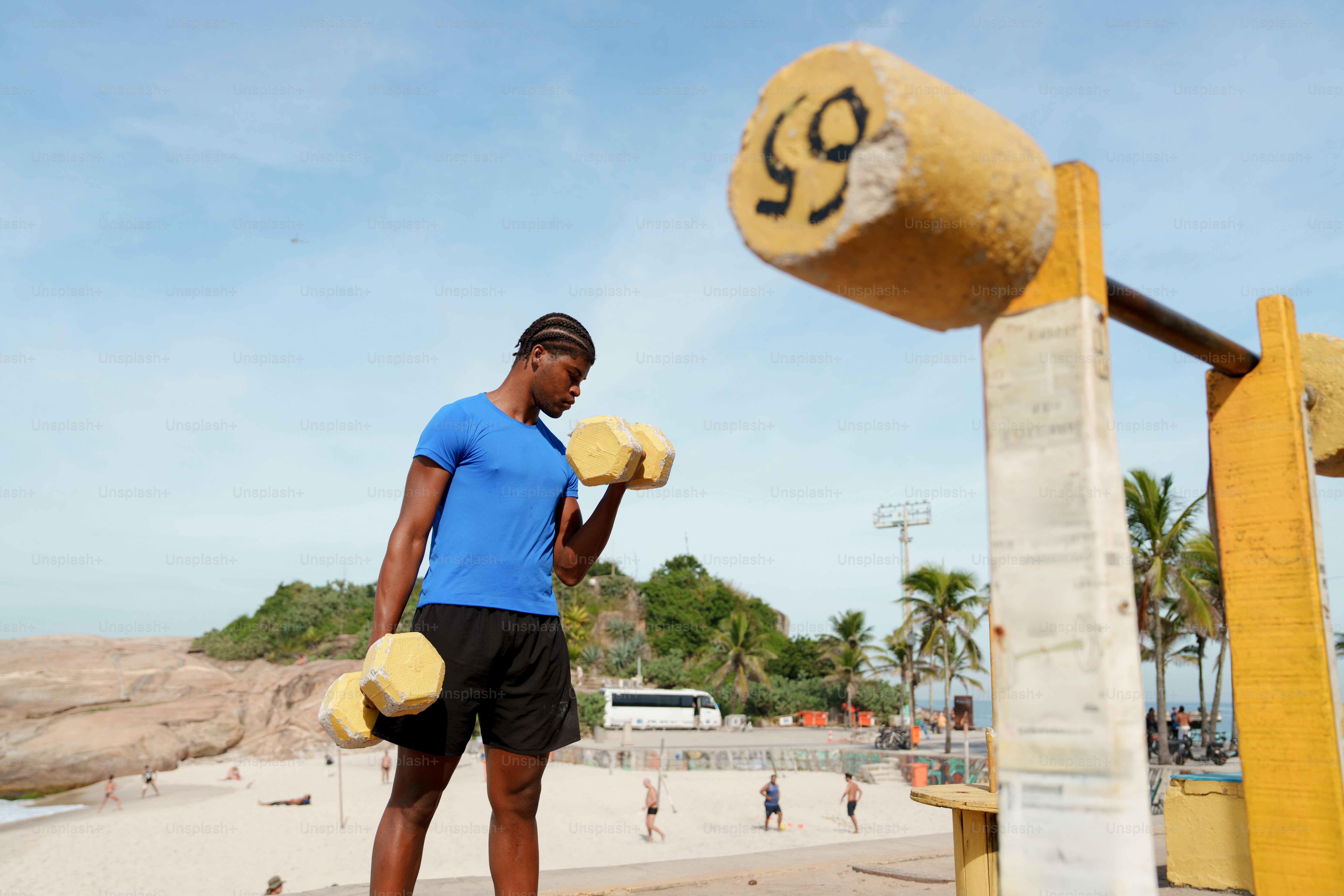 Young man lifting yellow block weights at an outdoor gym.