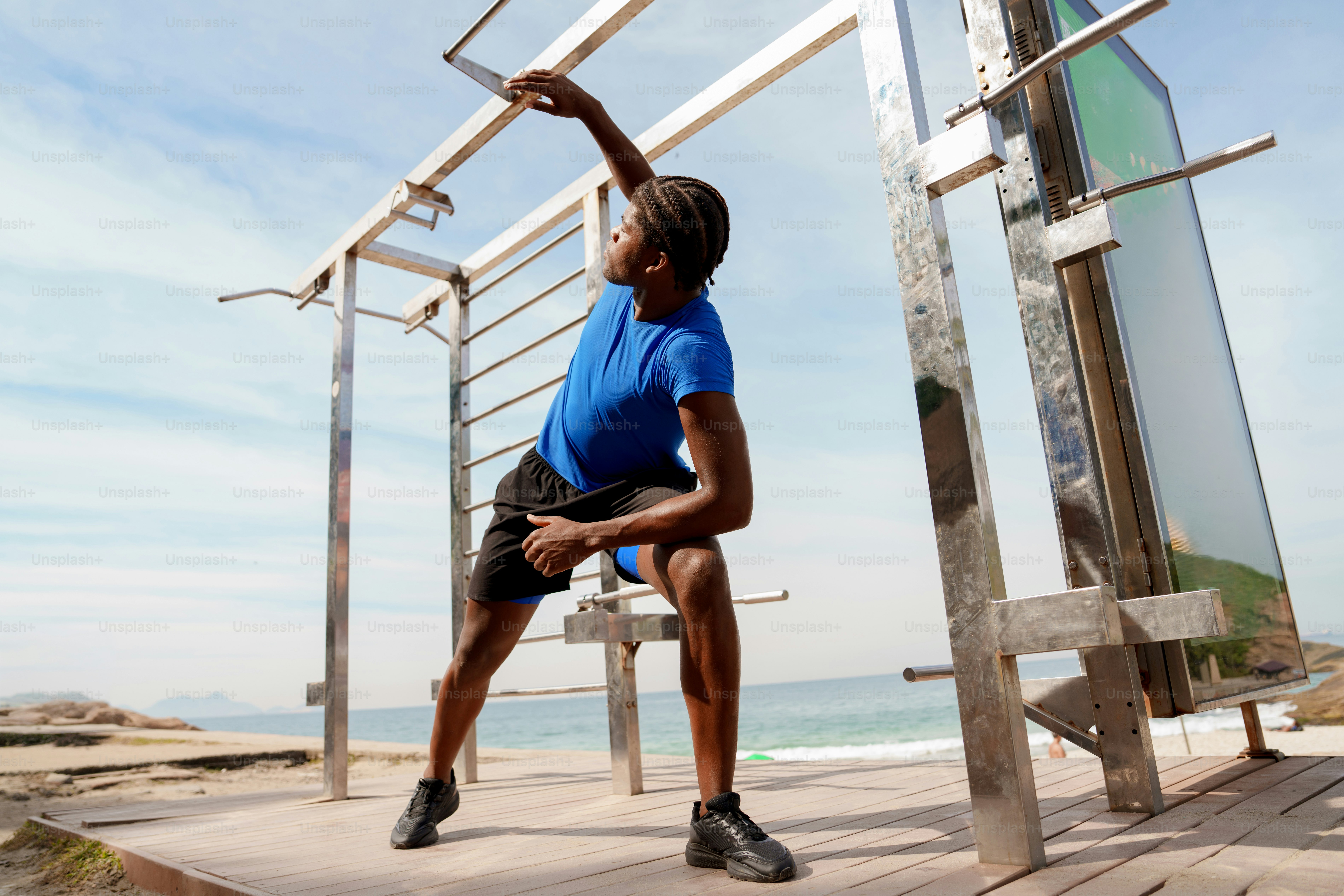 Young man exercising on an outdoor gym by the beach.