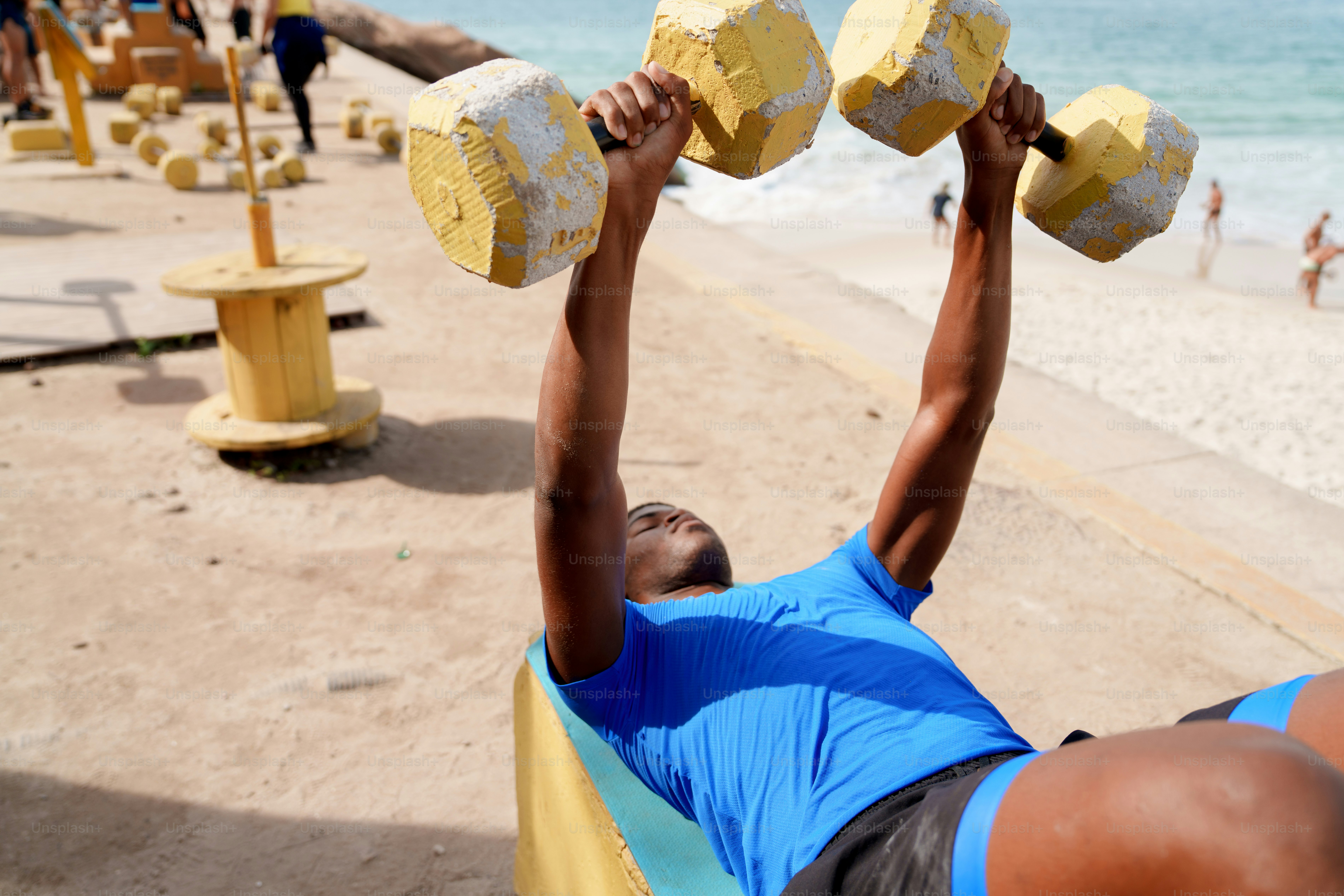 A person lifts yellow dumbbells while exercising outdoors.