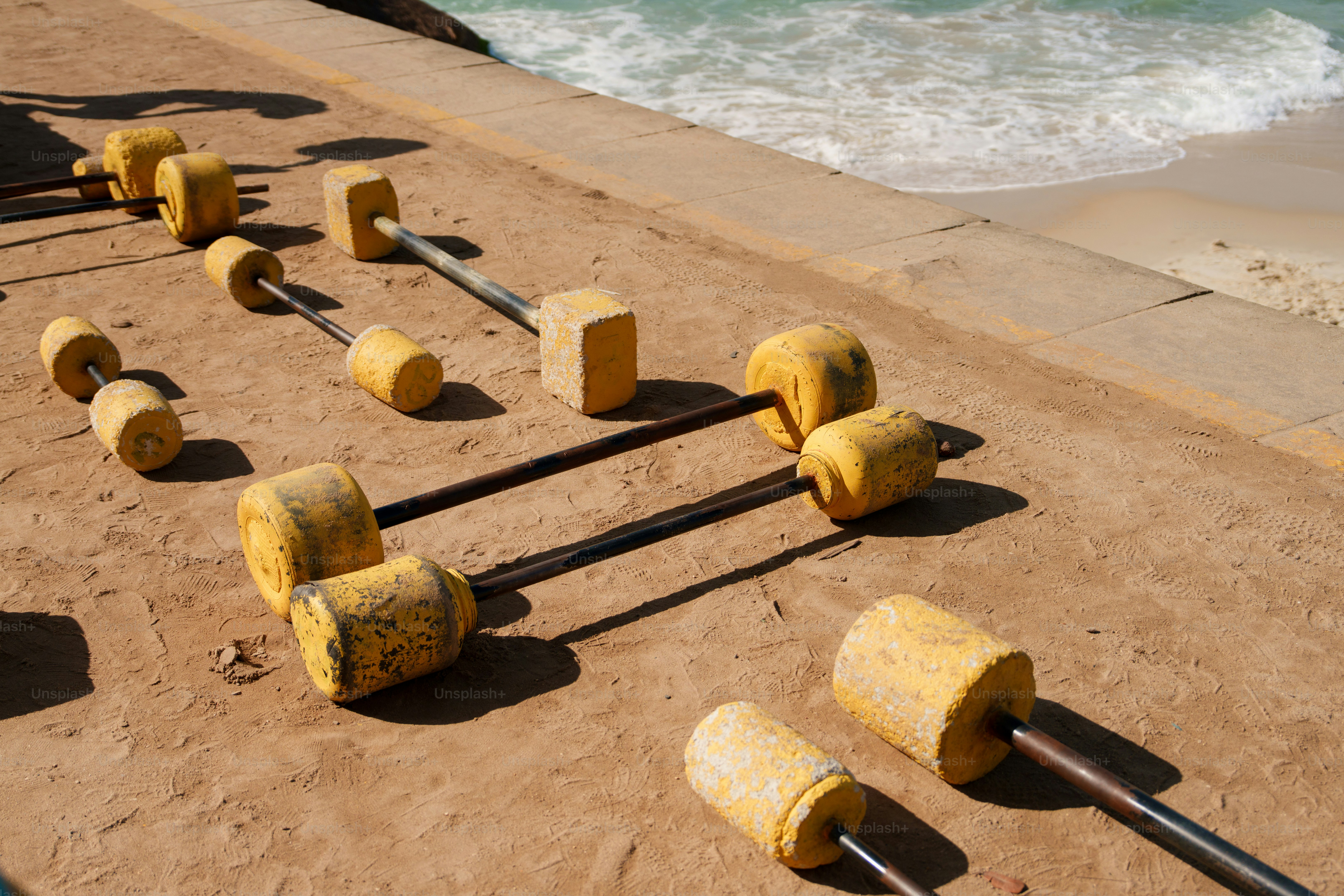 Yellow buoys and ropes on the sand near the ocean.