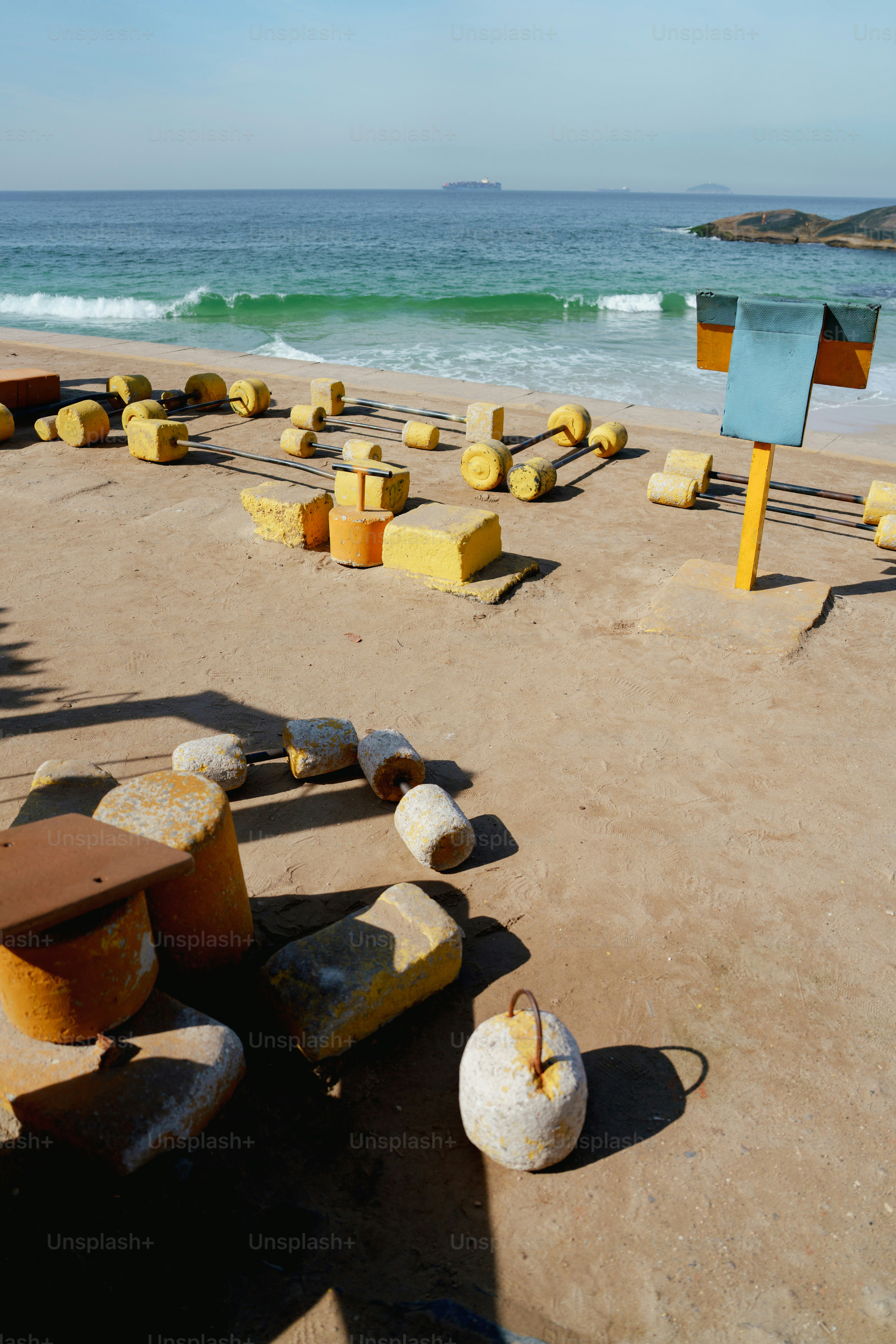 Yellow and orange geometric sculptures scattered on a sunny beach.