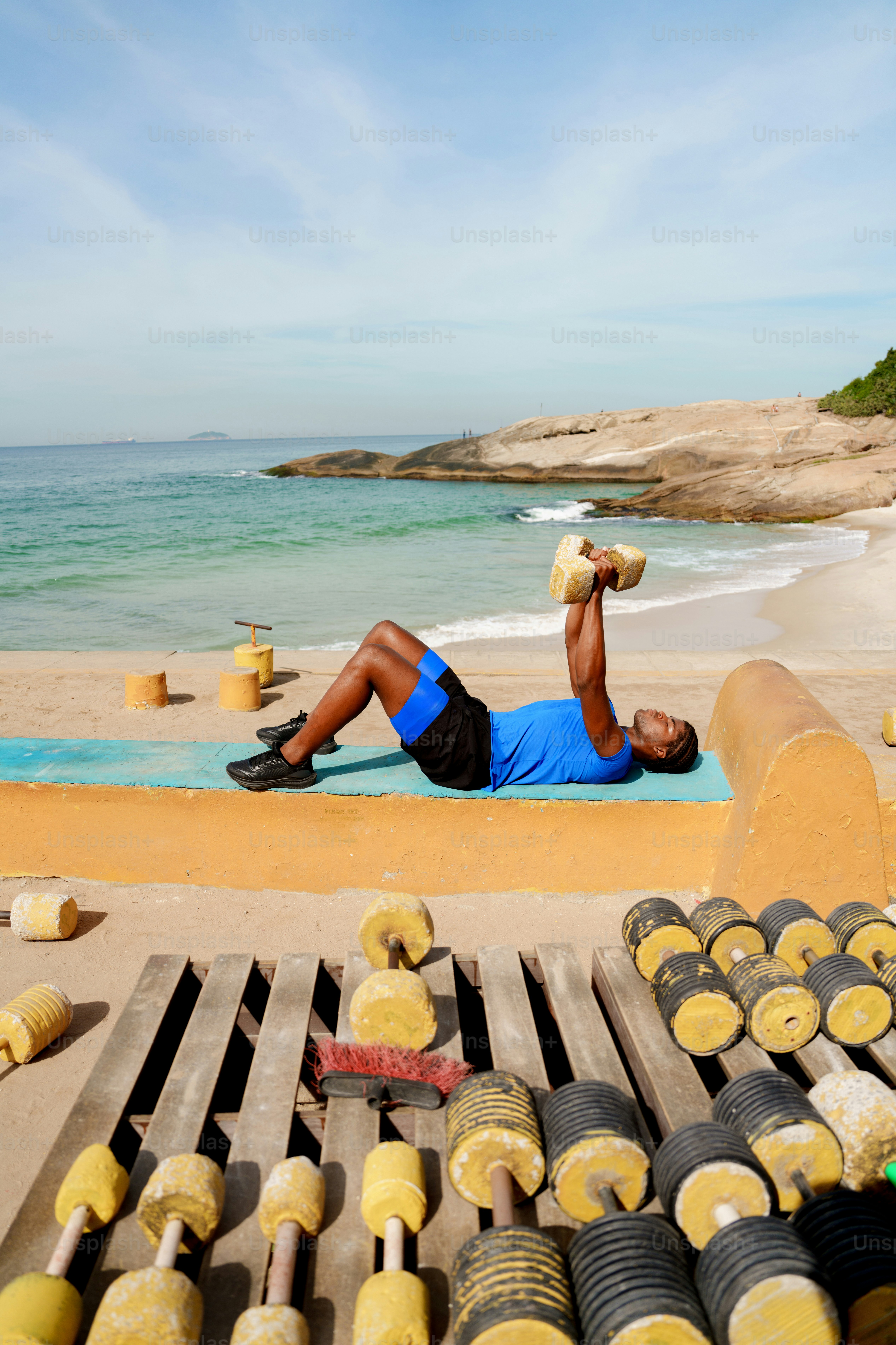 Athletic man exercising with weights by the ocean.