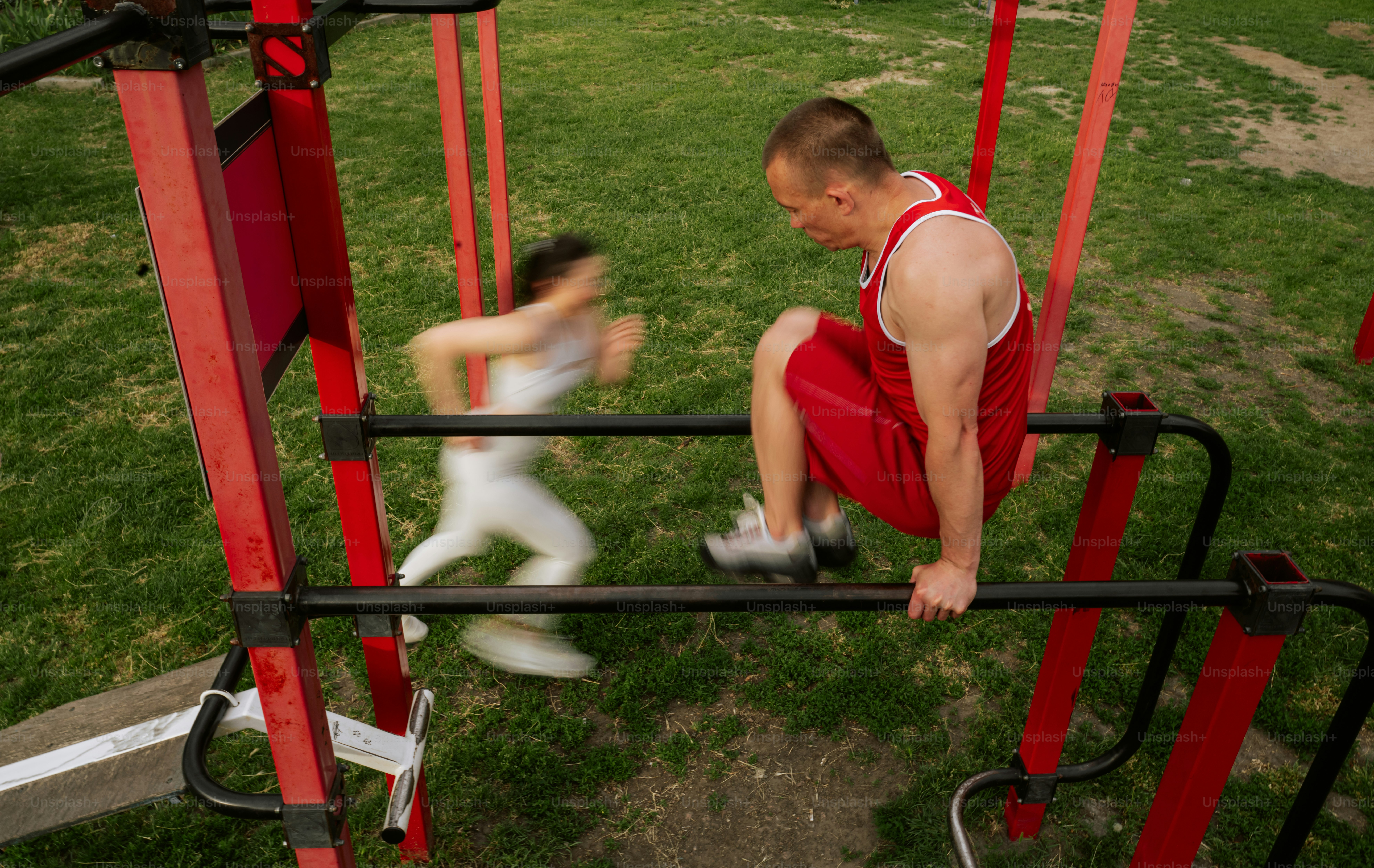 Man exercising on parallel bars while child runs past