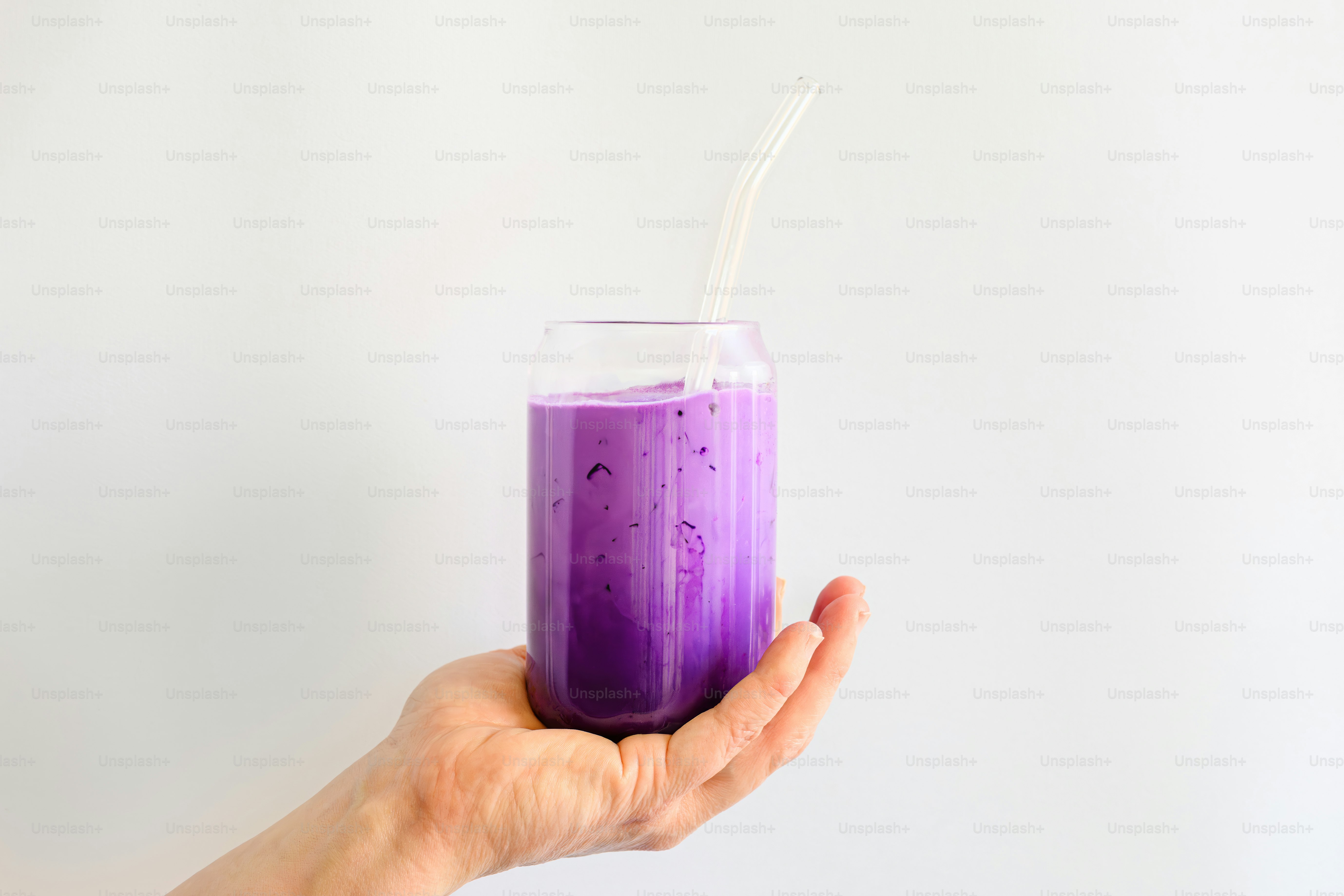 A hand holds a vibrant purple smoothie.