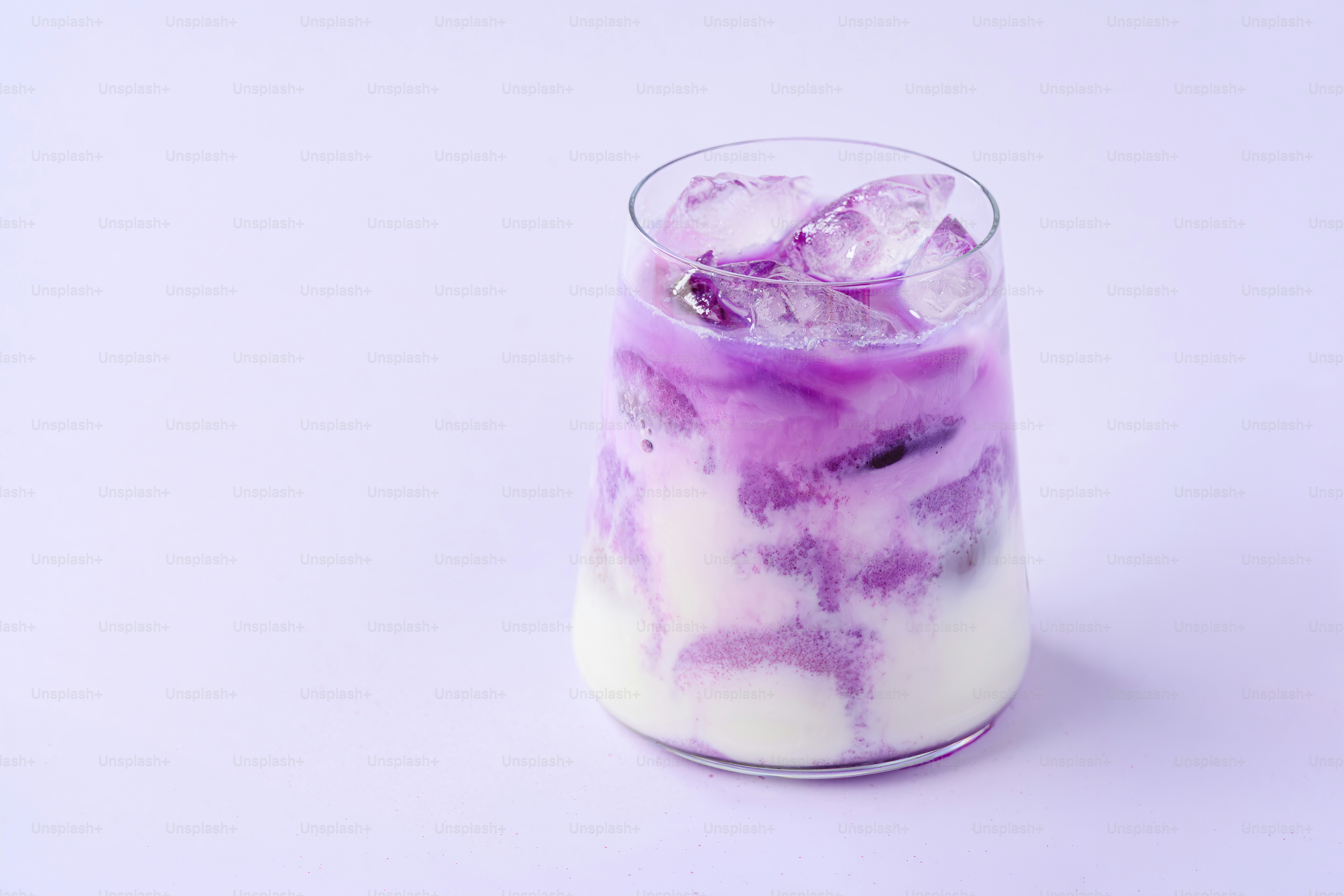A glass of purple and white swirled drink with ice.
