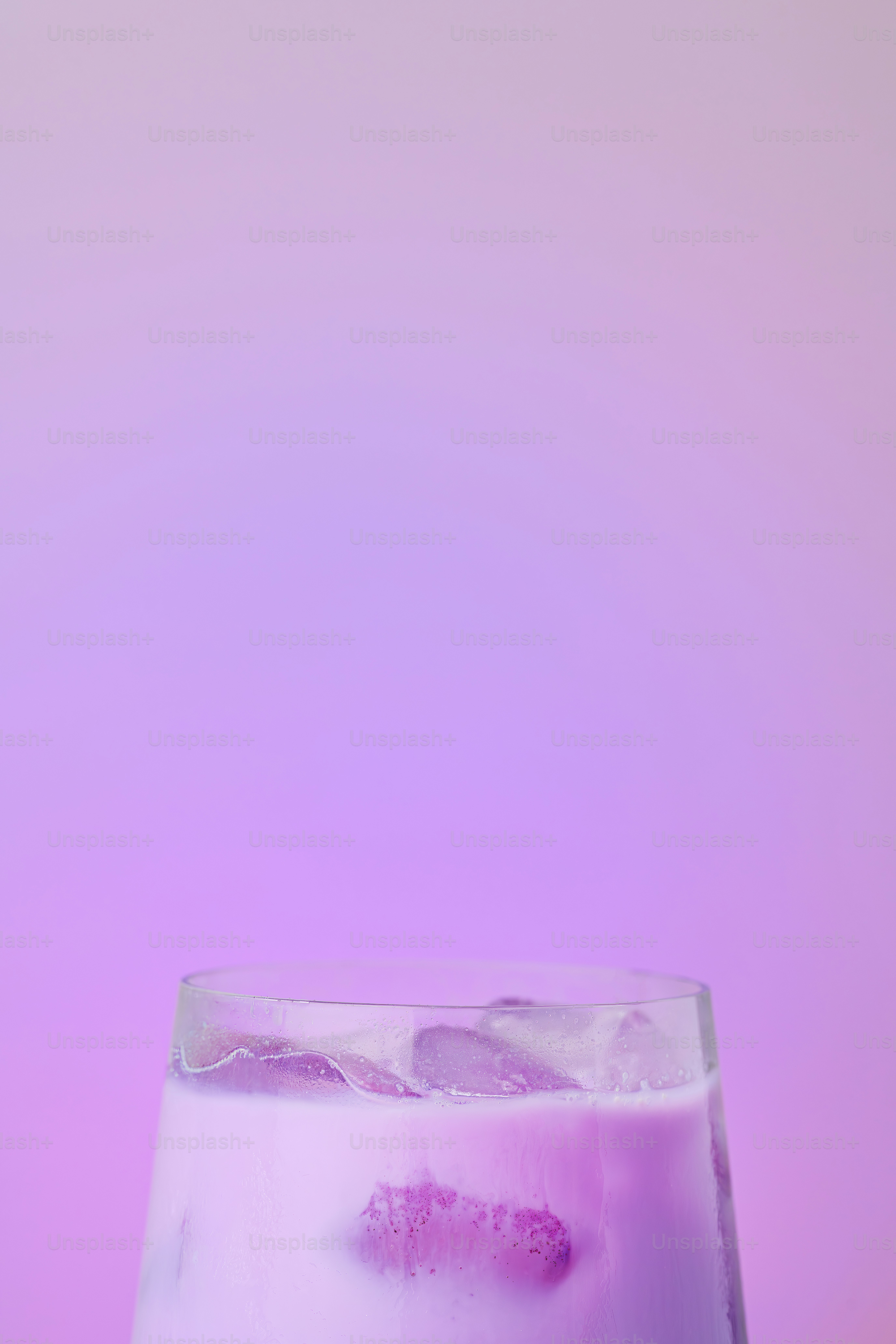 A glass of purple iced drink against a purple background.