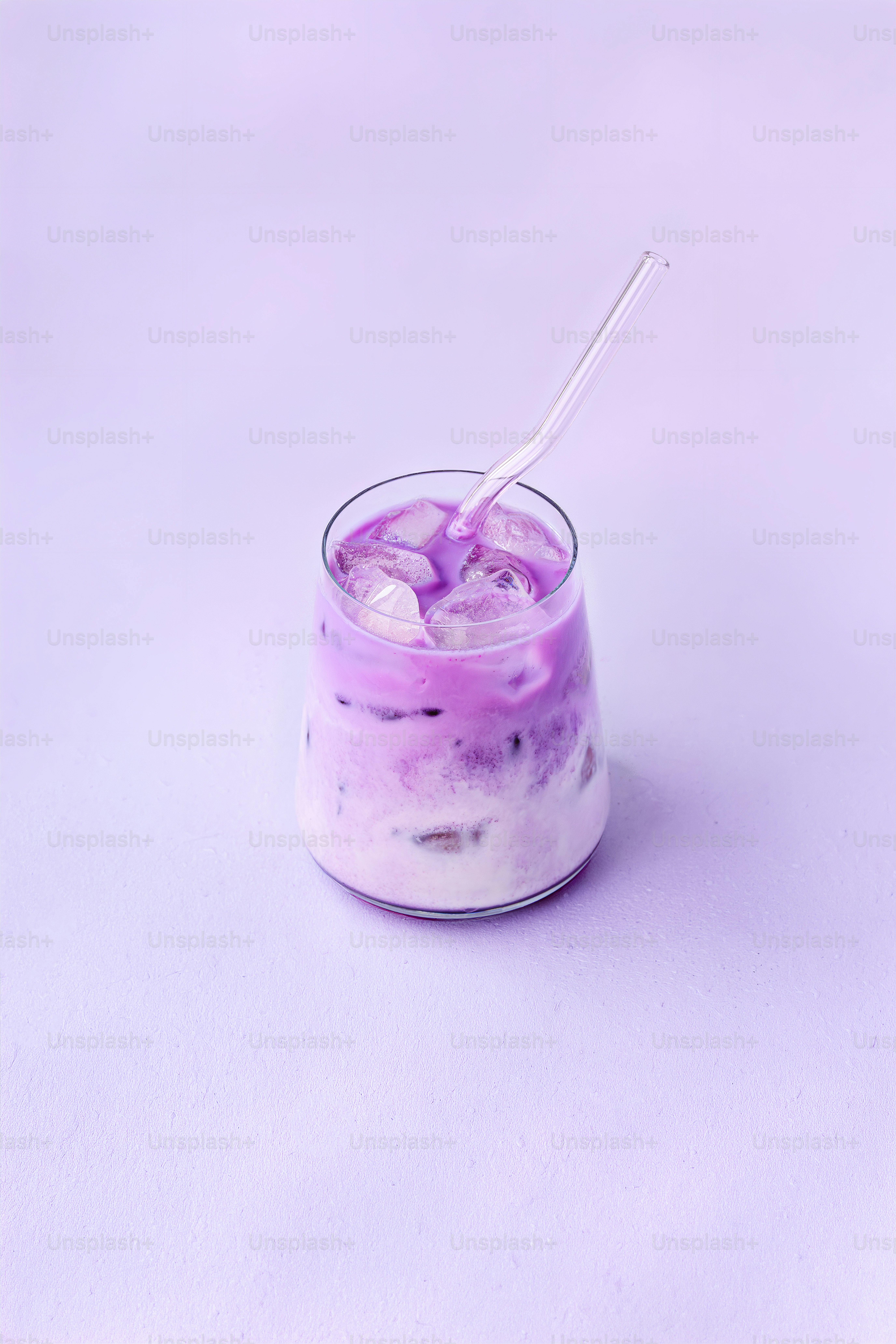 A glass of purple iced latte with a straw.