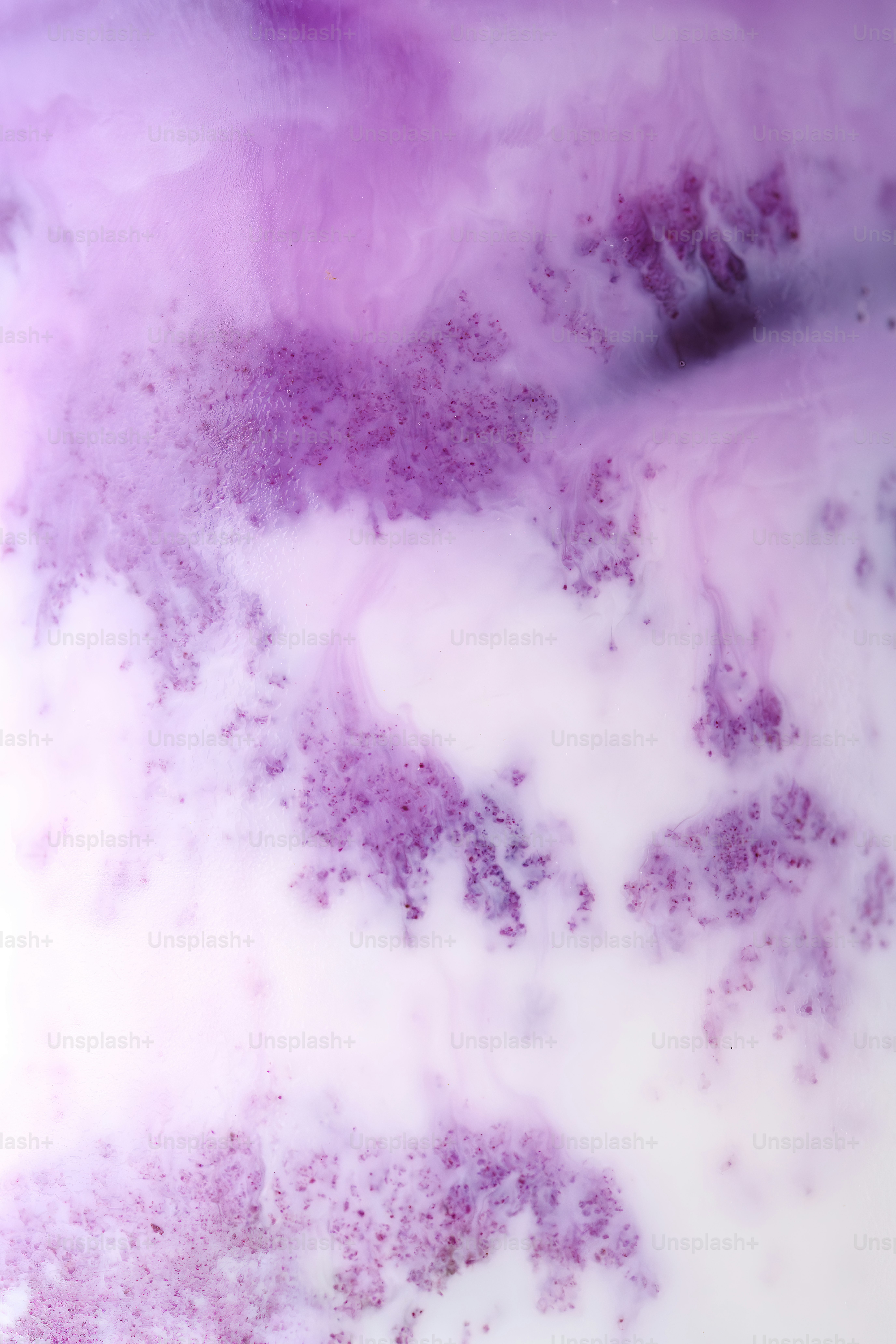 Purple liquid swirls into white, creating abstract patterns.
