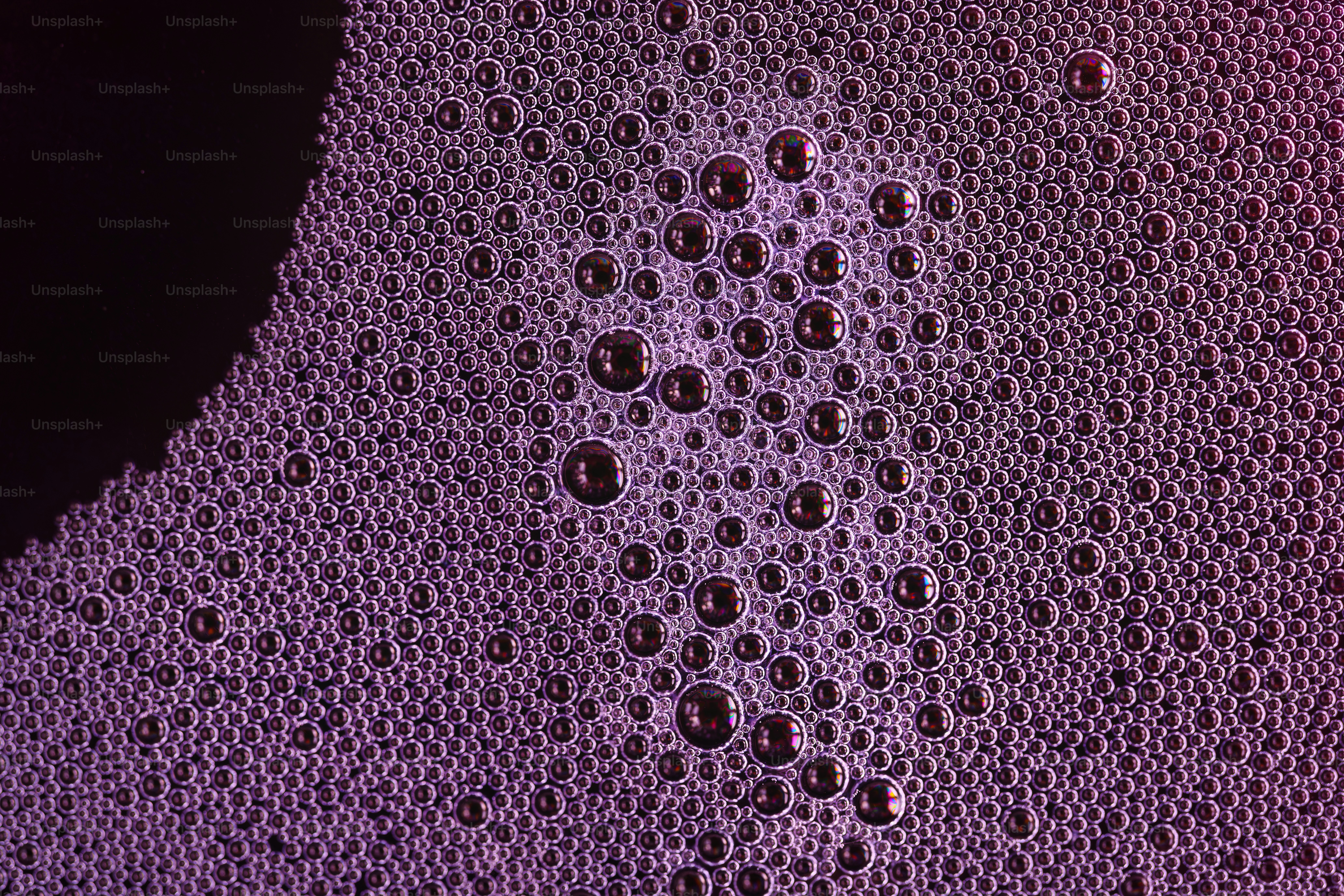 Purple foam with dark bubbles on a black surface.