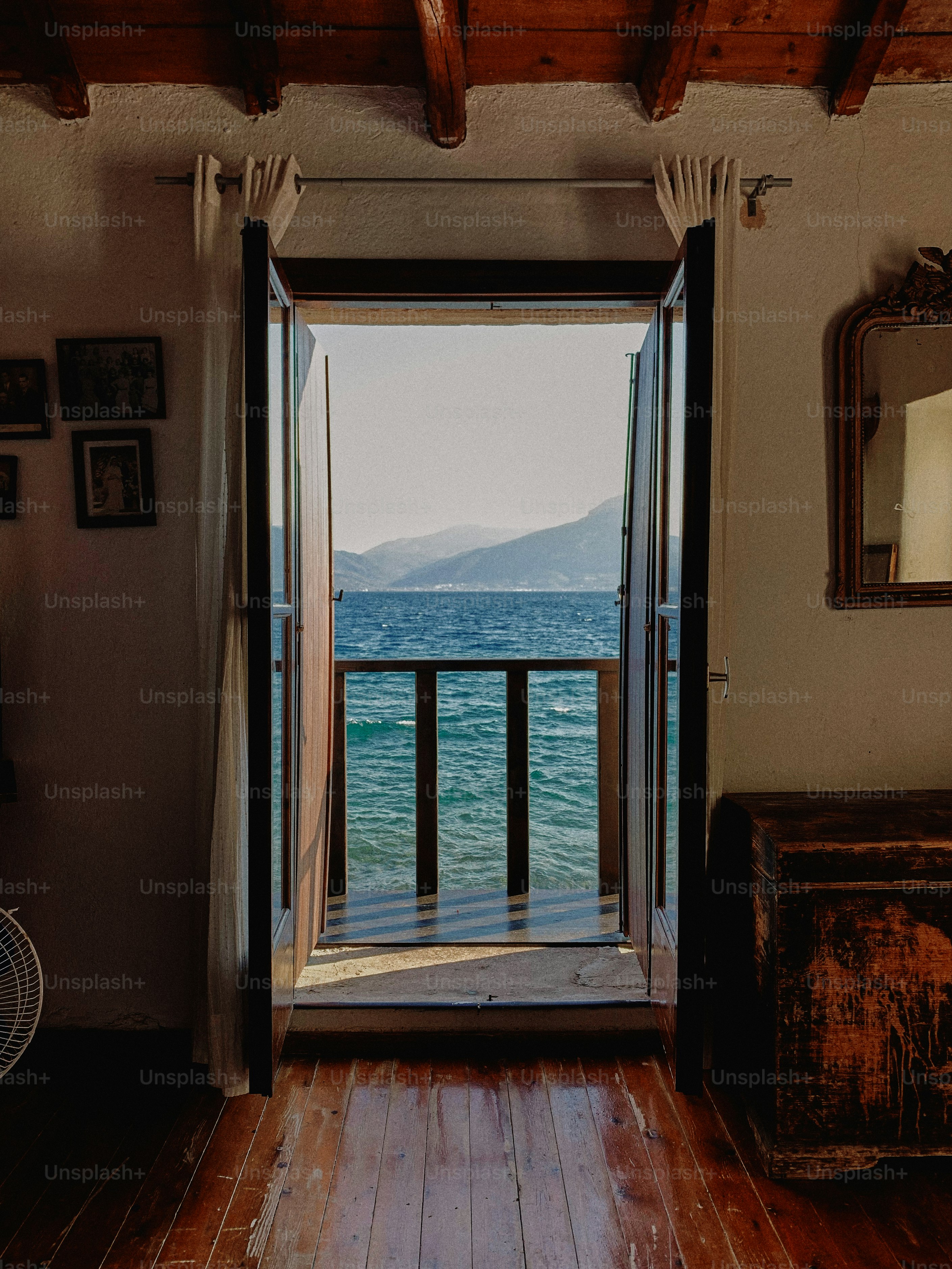Open door overlooks the serene sea and distant mountains.