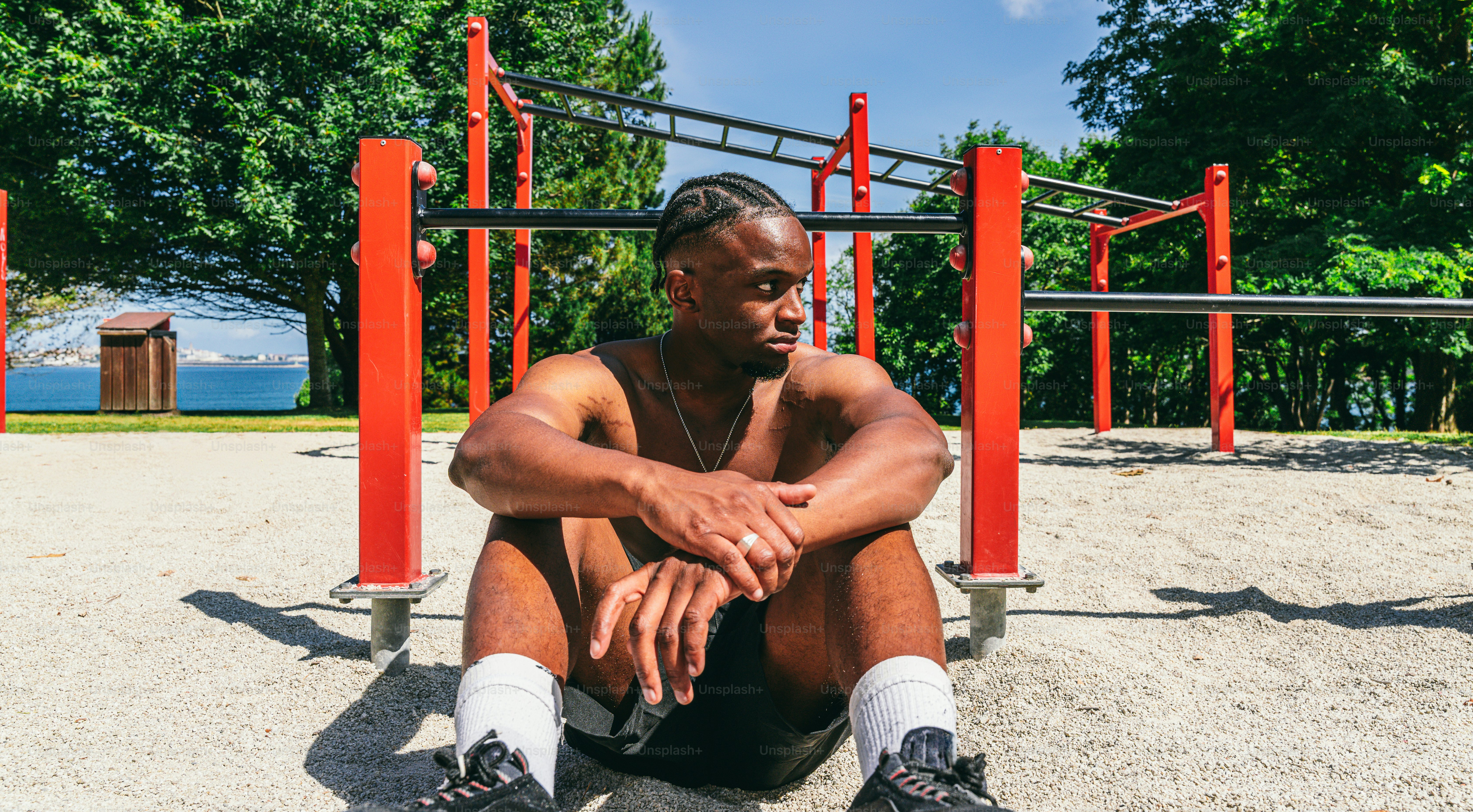 A shirtless man resting in an outdoor calisthenics park.
