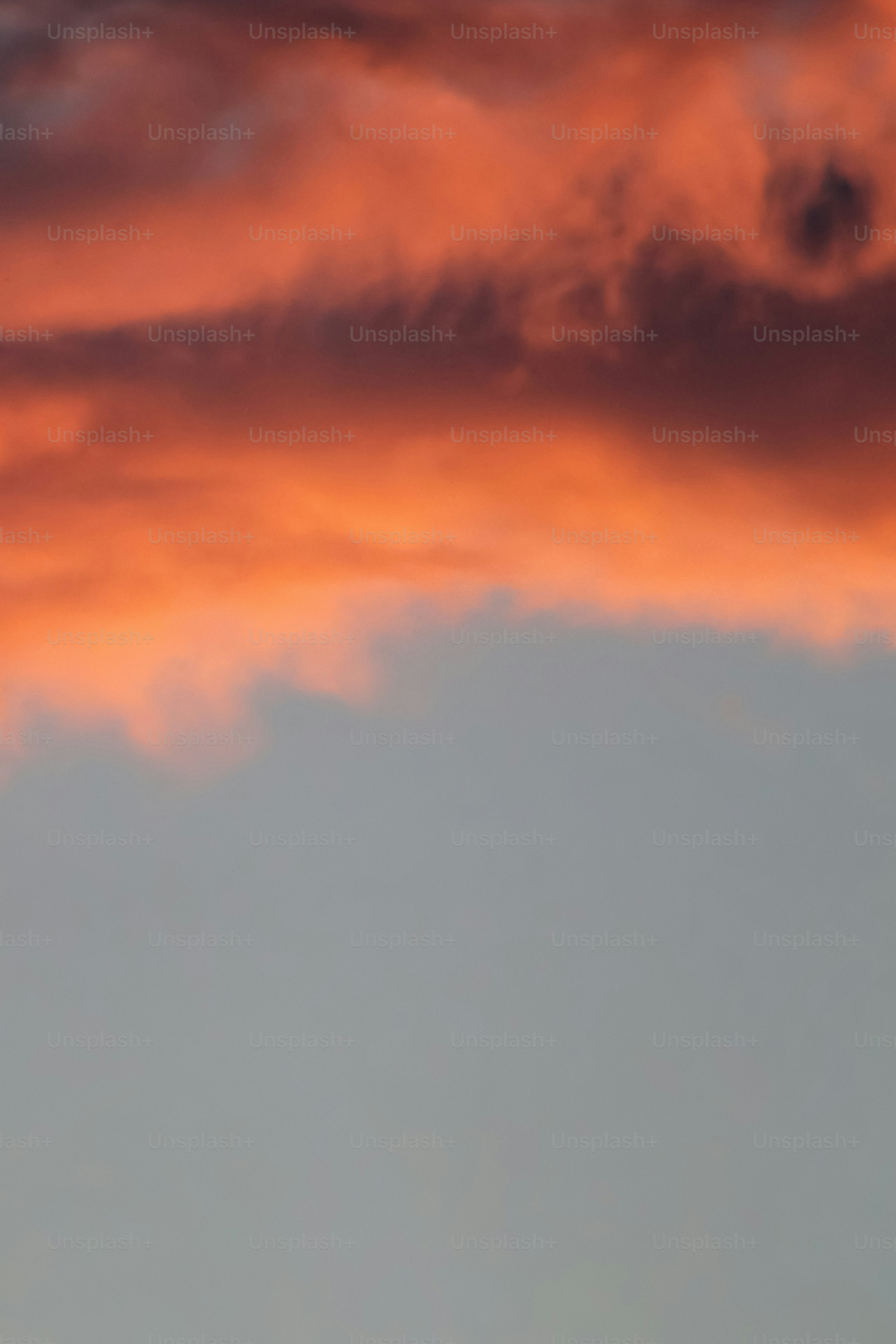 Awan oranye dan merah menentang langit abu-abu biru.