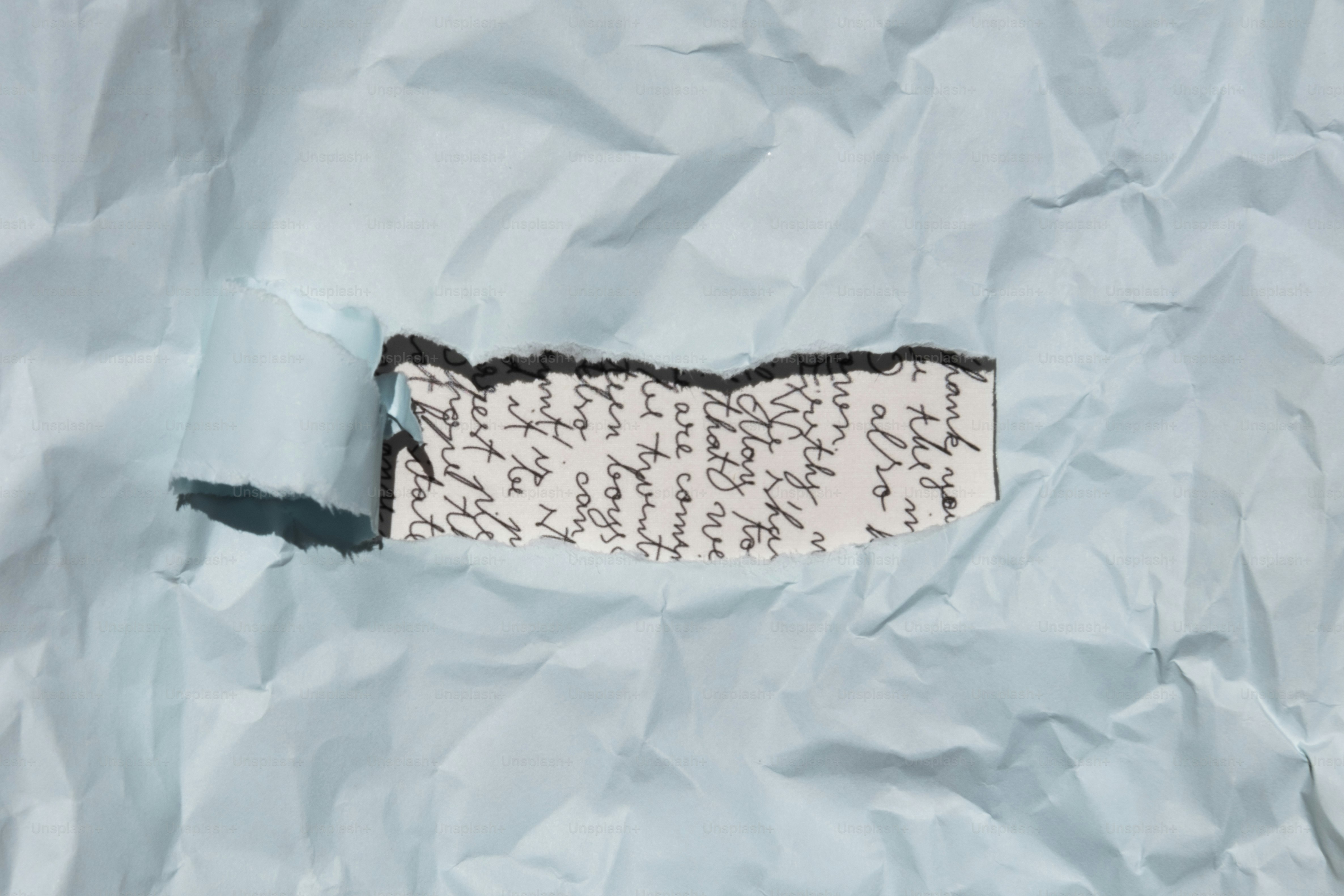 A torn piece of handwritten paper on crumpled blue background. photo ...