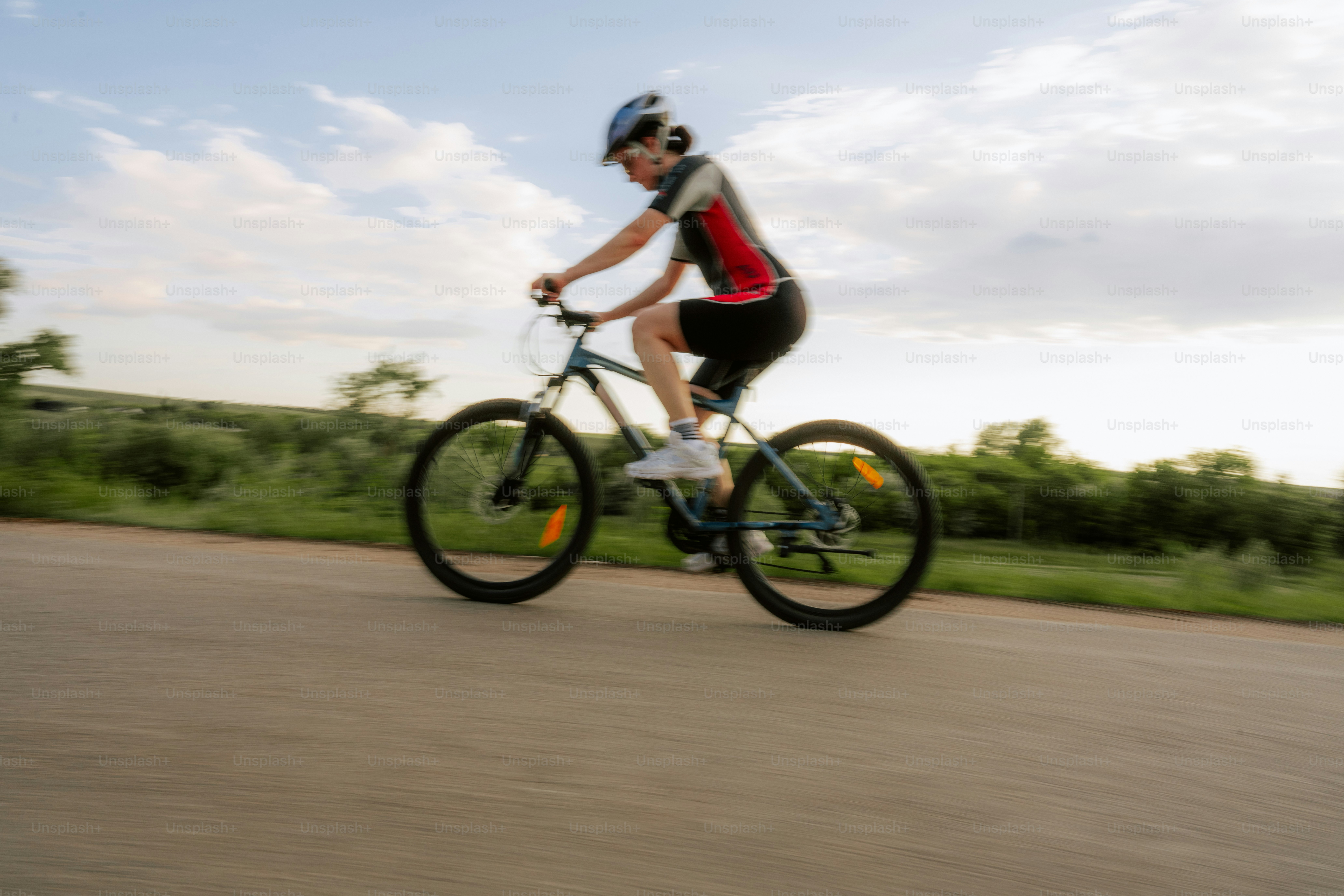Une personne faisant du vélo sur une route sous un ciel nuageux.