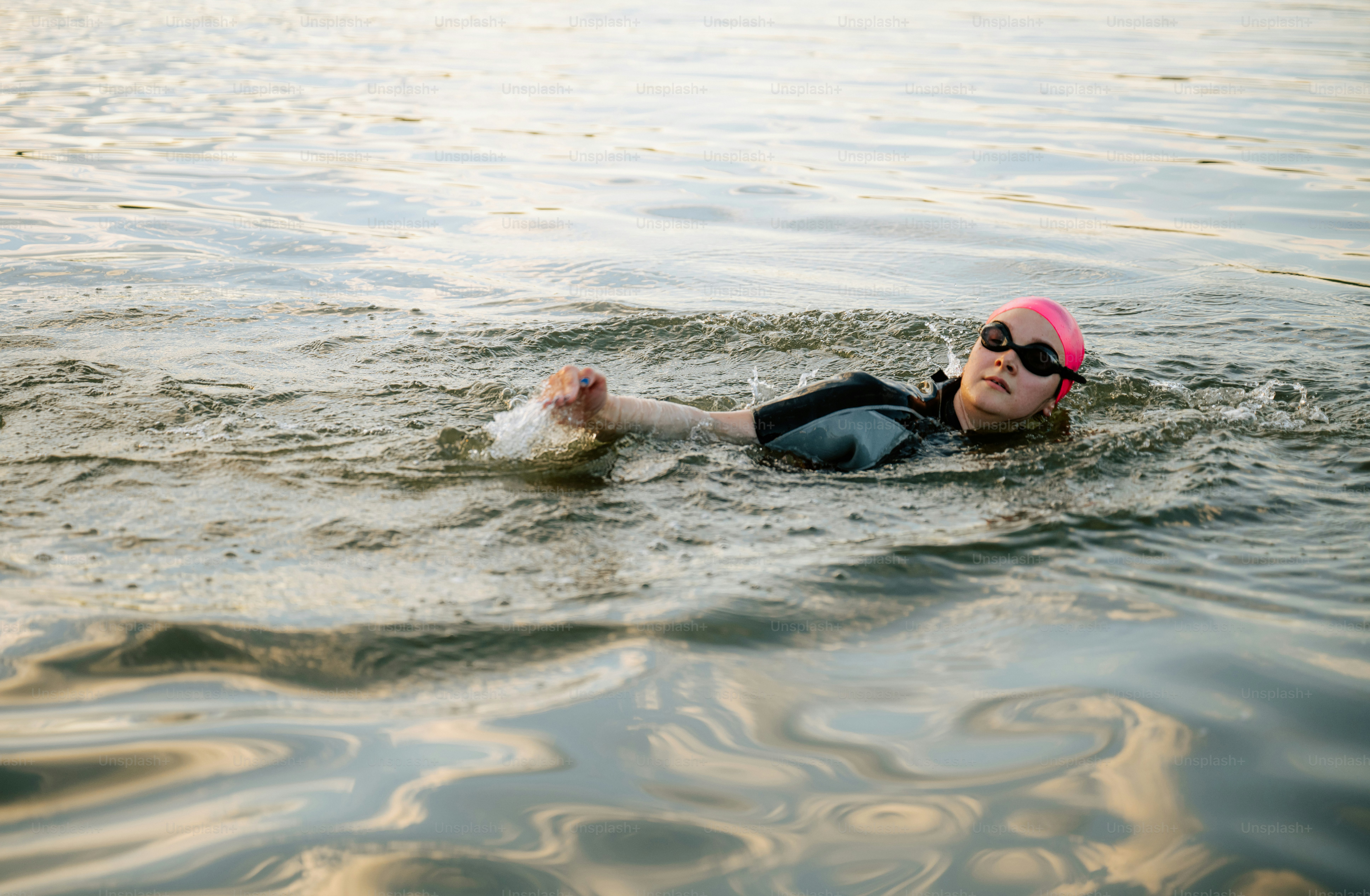 Un nageur en casquette rose et lunettes de protection dans l’eau.