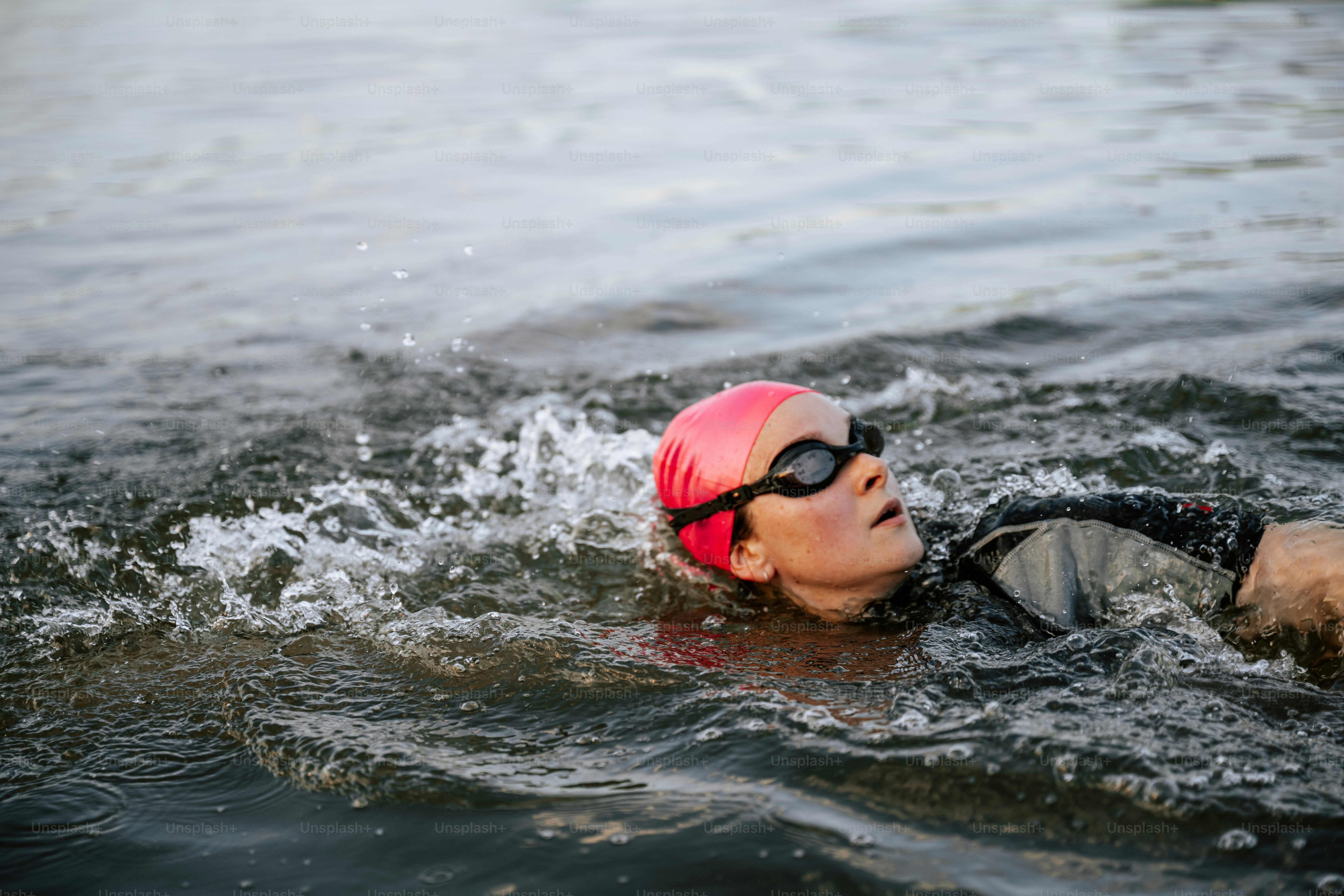 Nageuse portant une casquette rose et des lunettes dans l’eau.