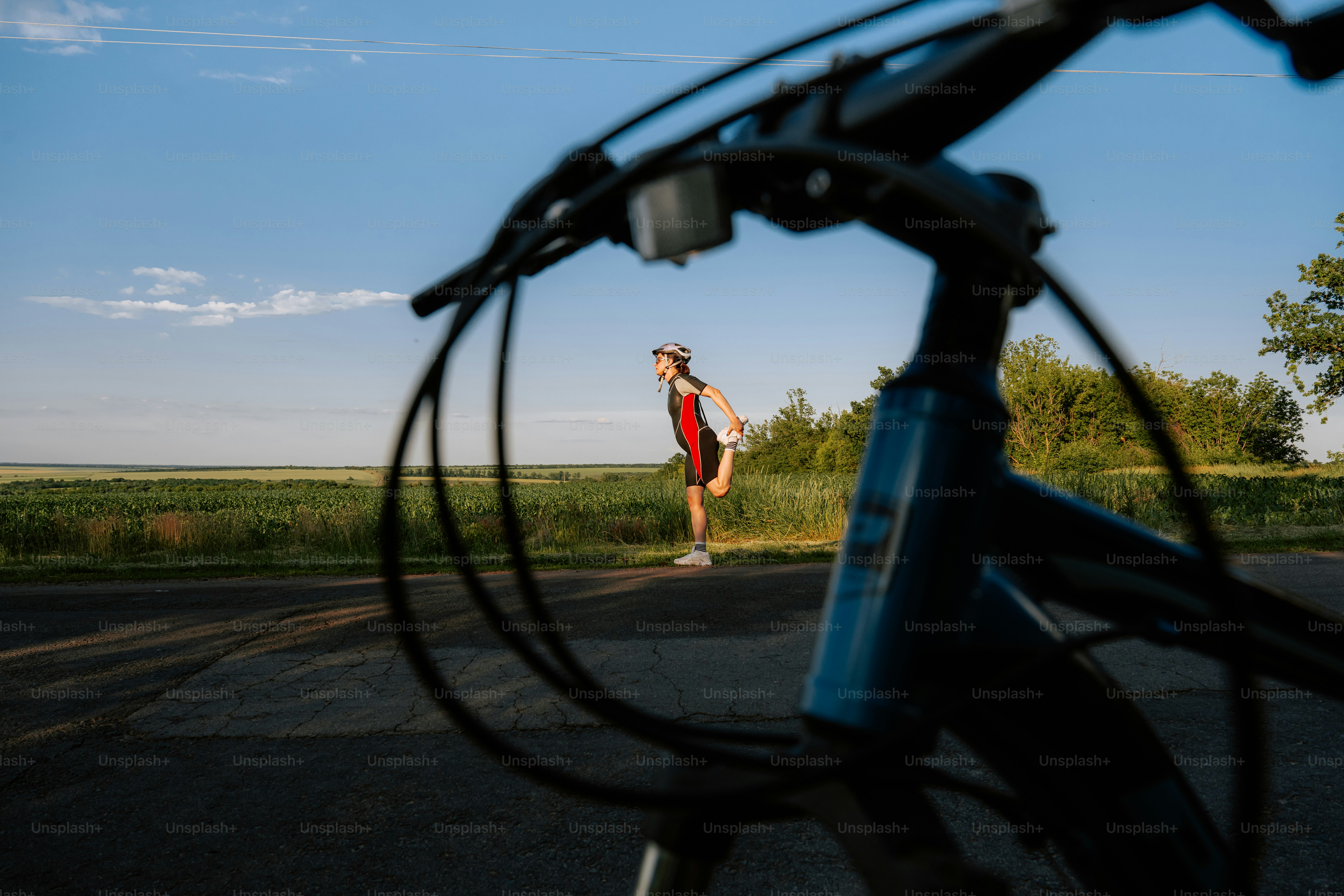 Cycliste se reposant sur une route rurale au coucher du soleil.