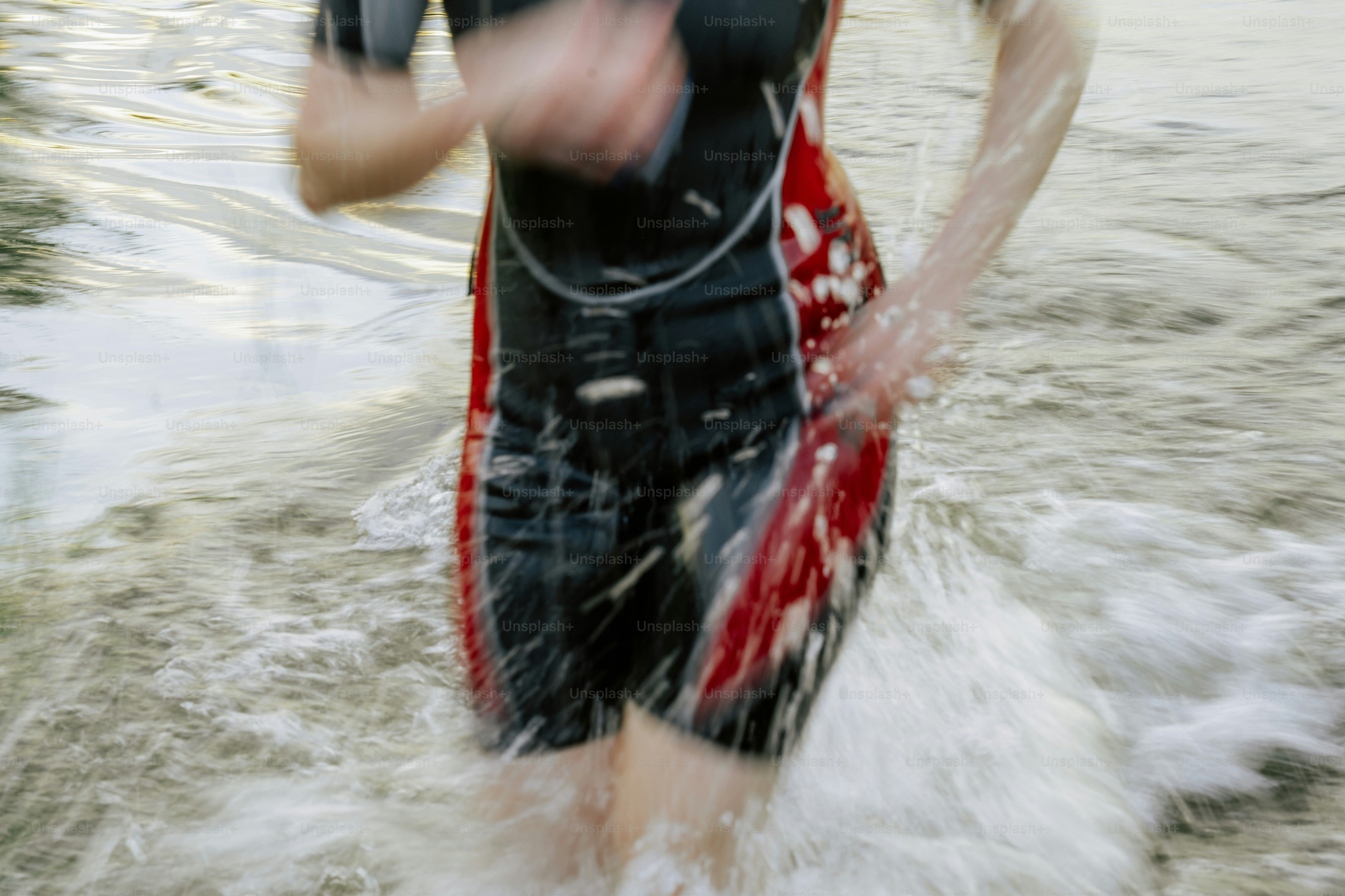 Une personne en combinaison courant dans l’eau éclaboussée.