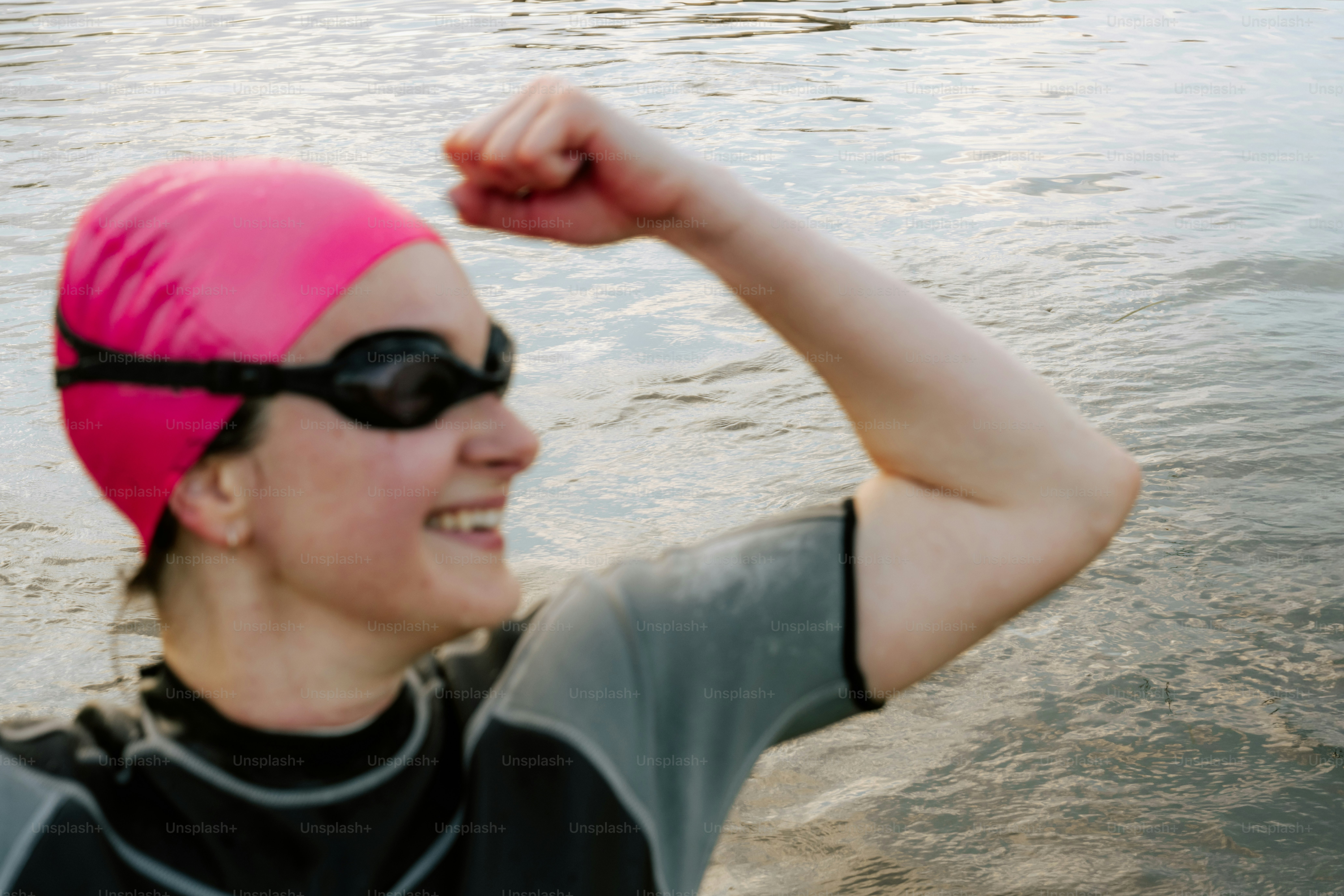 Nageur en casquette rose, bras fléchi, souriant.