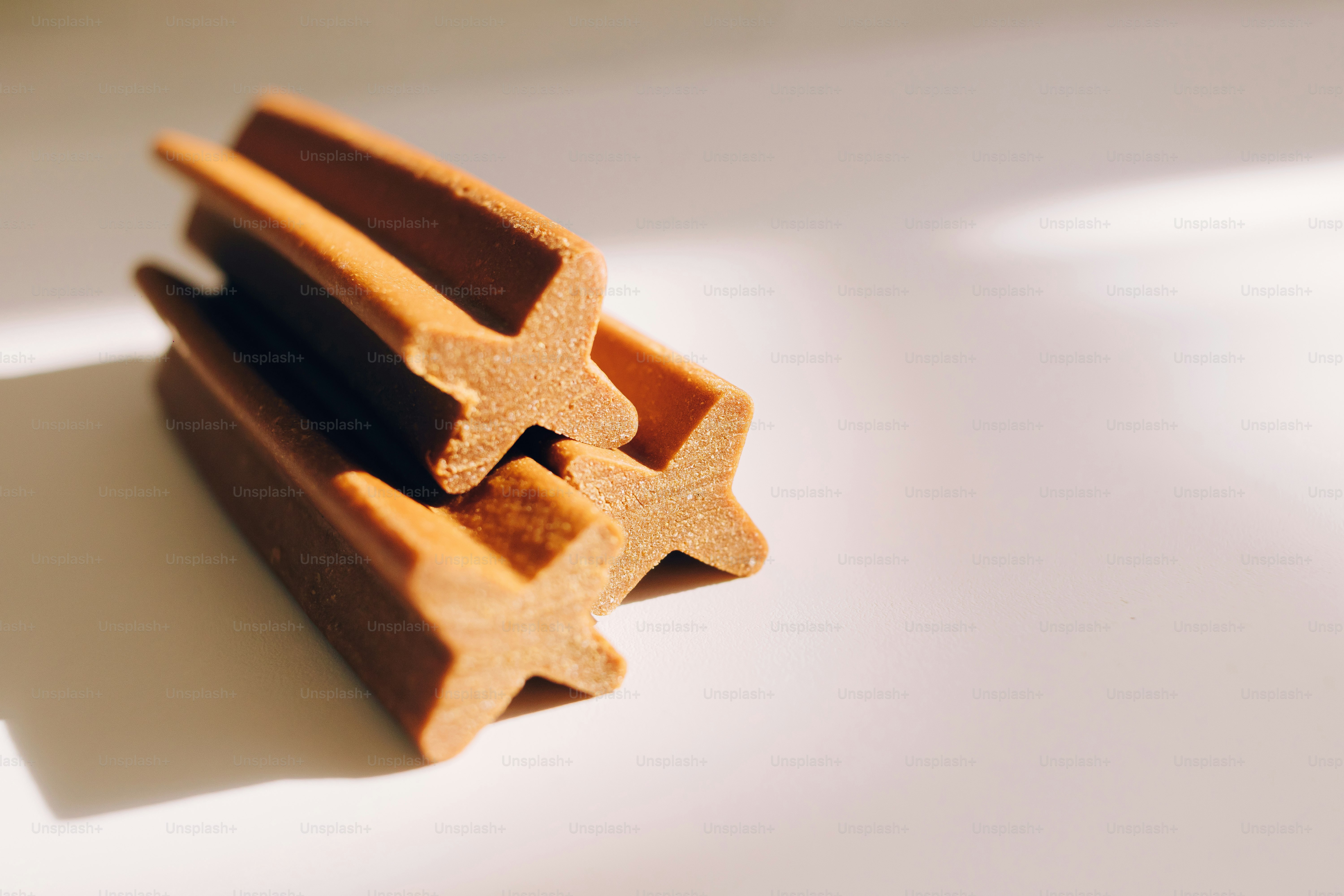 Due masticabili dentali marroni a forma di stella su superficie bianca.