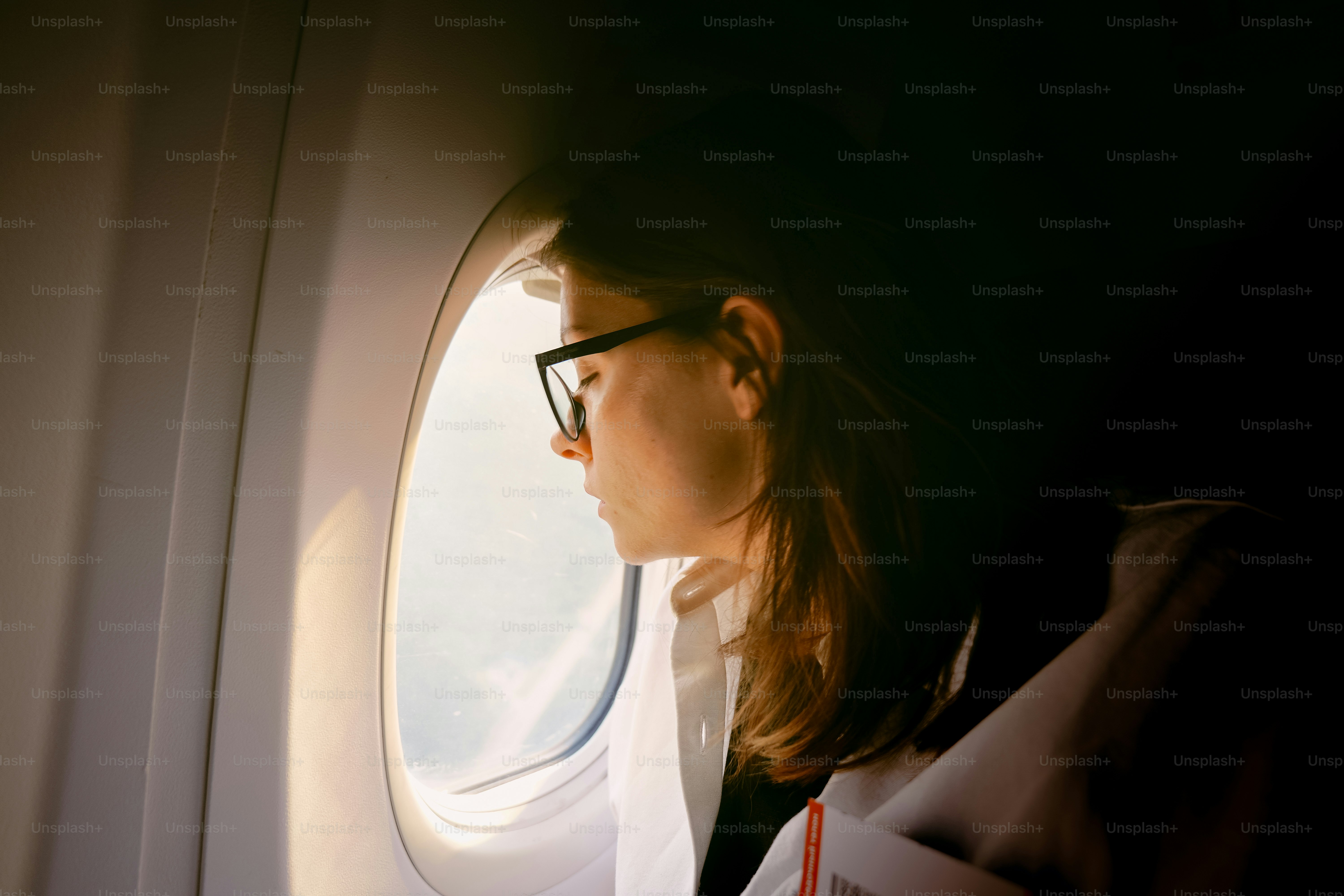 明るい飛行機の窓の外を覗く乗客