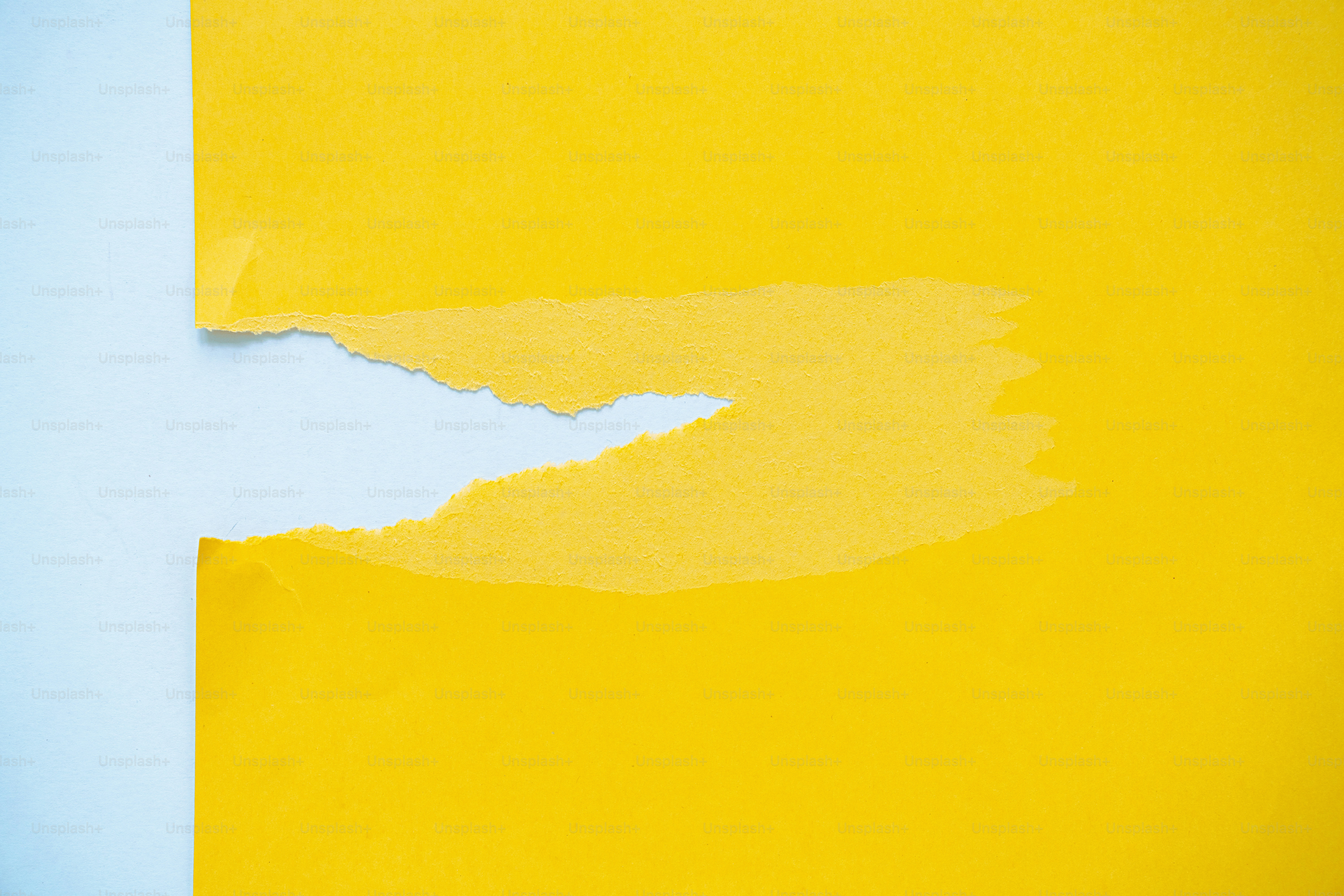 Papier jaune déchiré révélant un fond bleu clair.