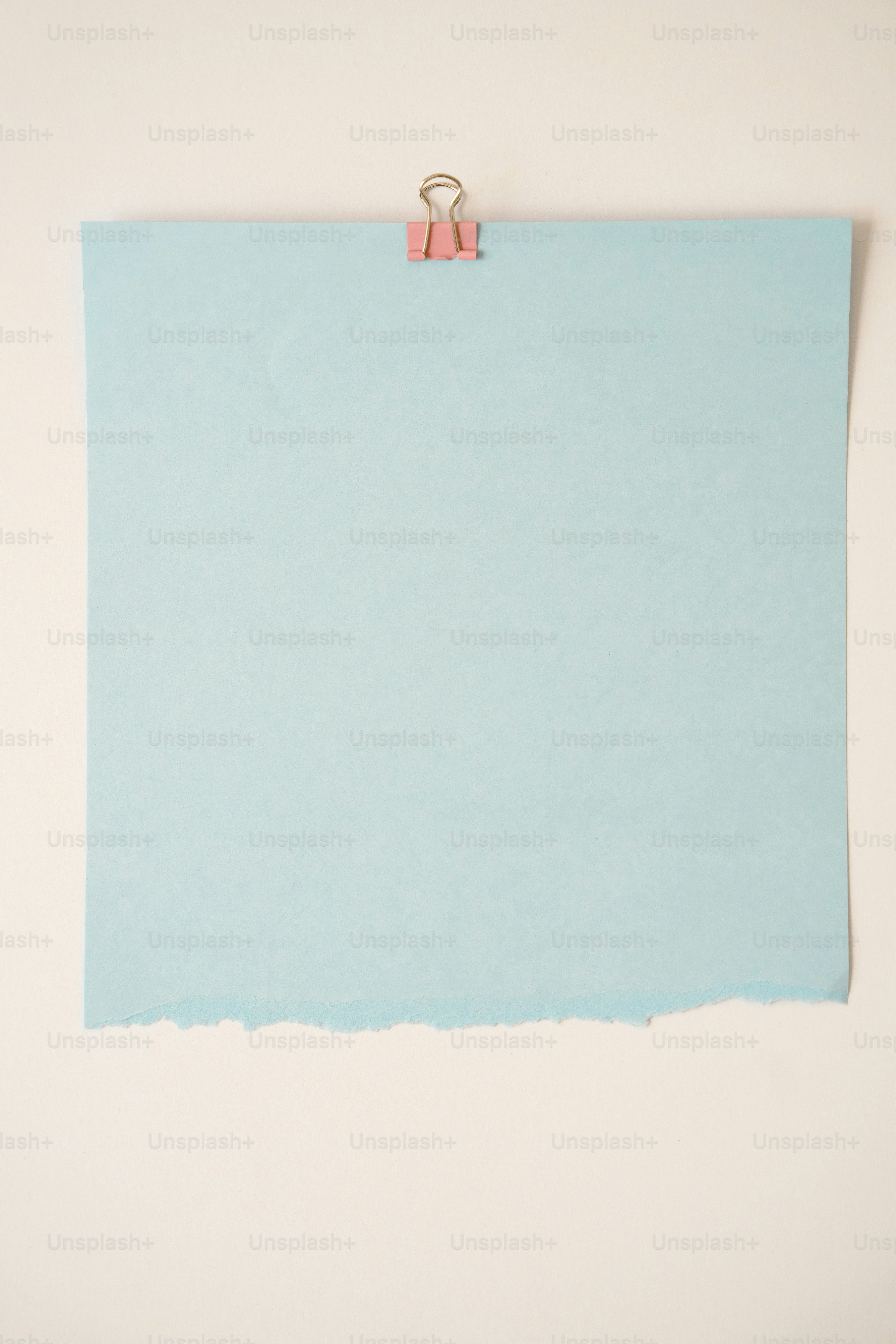 Du papier bleu clair avec pince rose sur fond blanc.