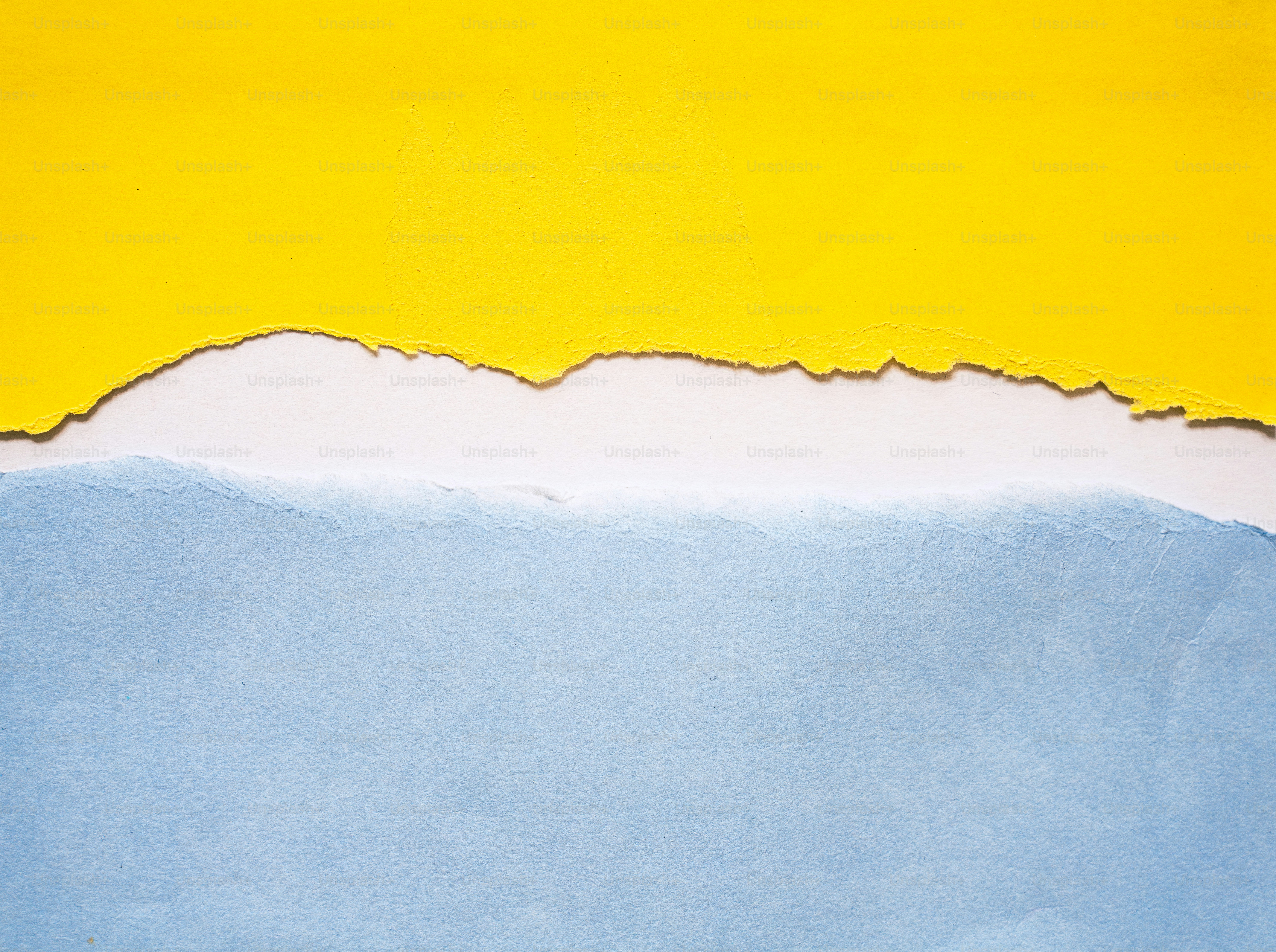 Du papier déchiré jaune et bleu avec un espace blanc entre les deux.