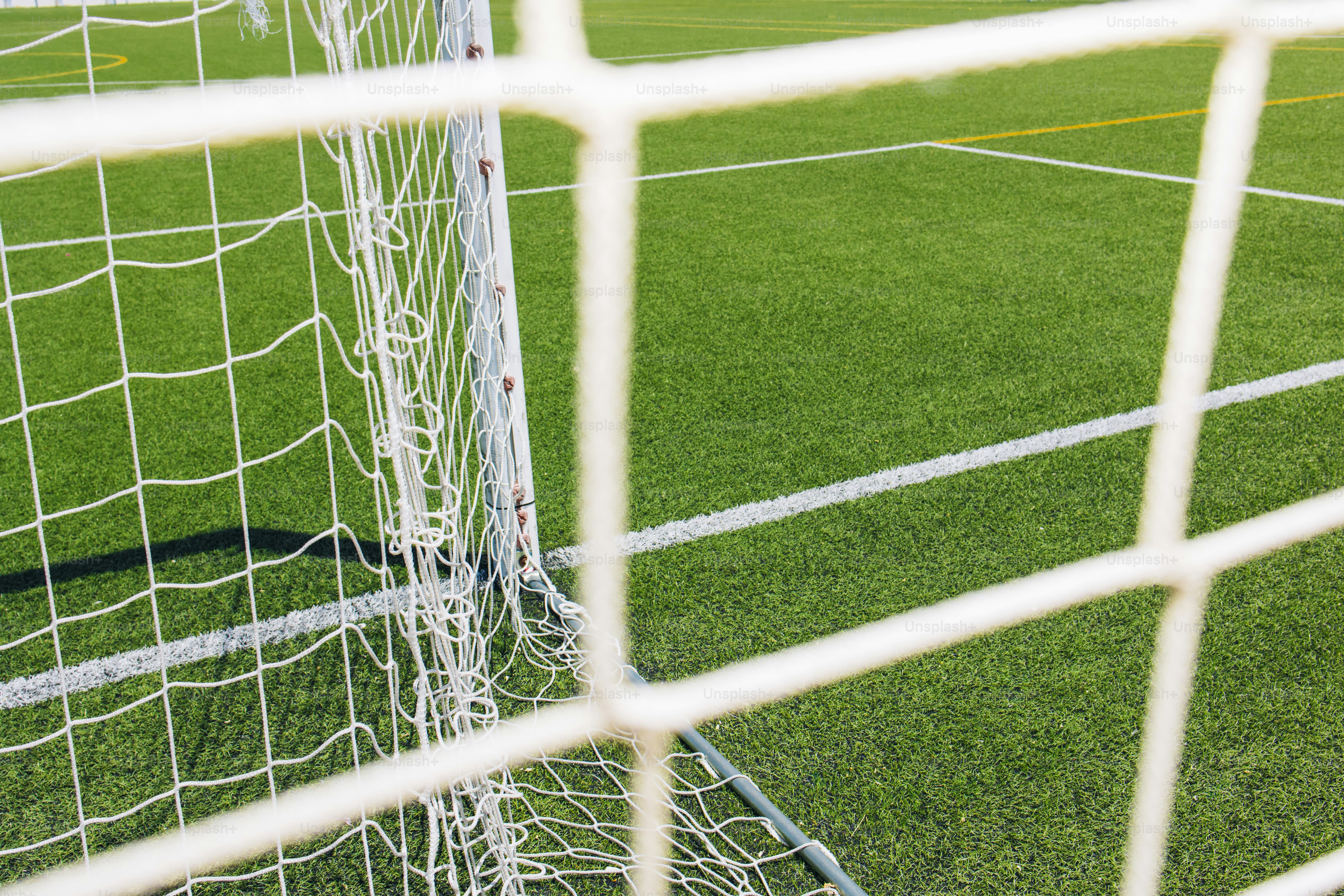 緑の芝生のフィールドに白いサッカーゴールネット。