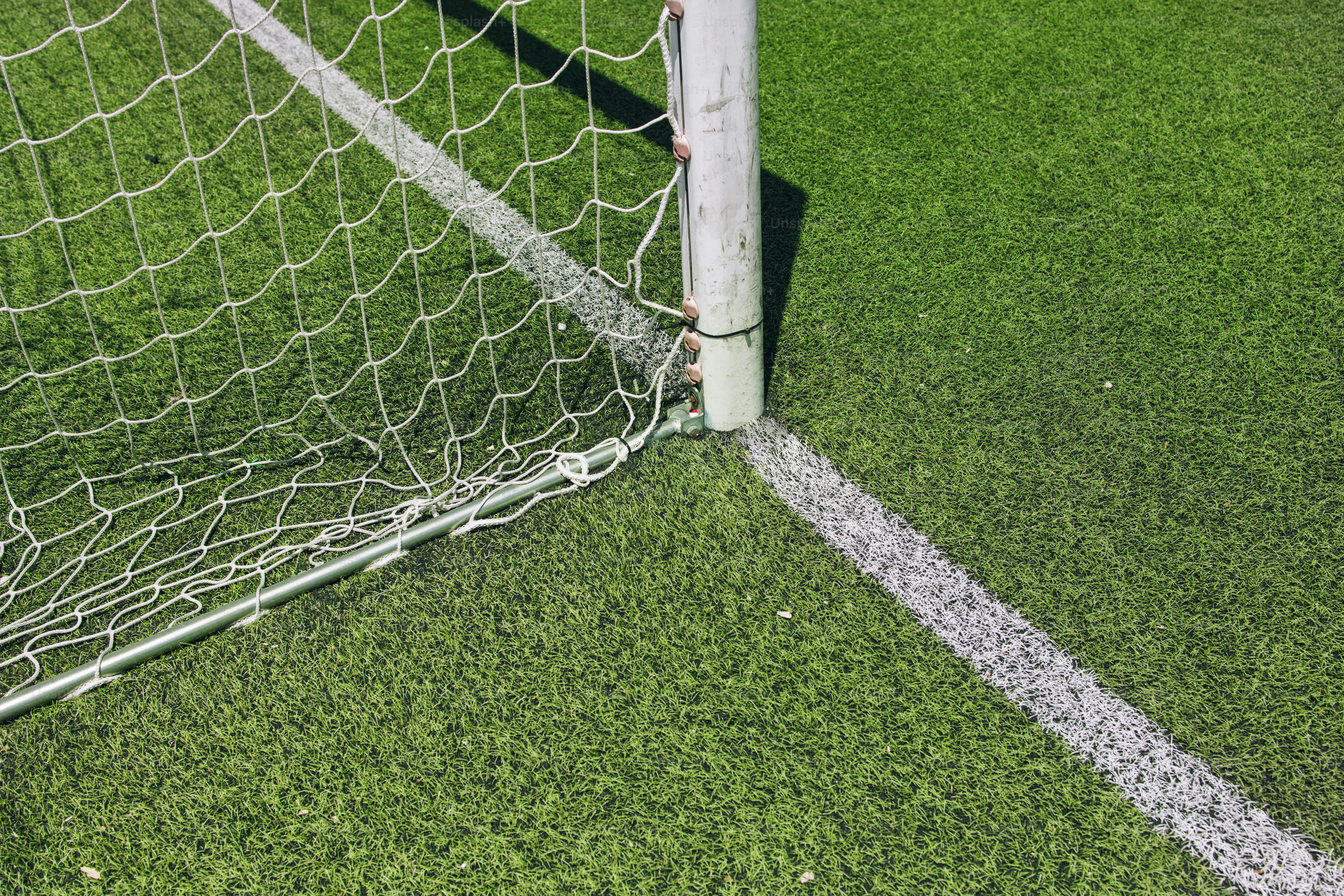 緑の人工芝の上にサッカーゴールポストとネットを設置しています。