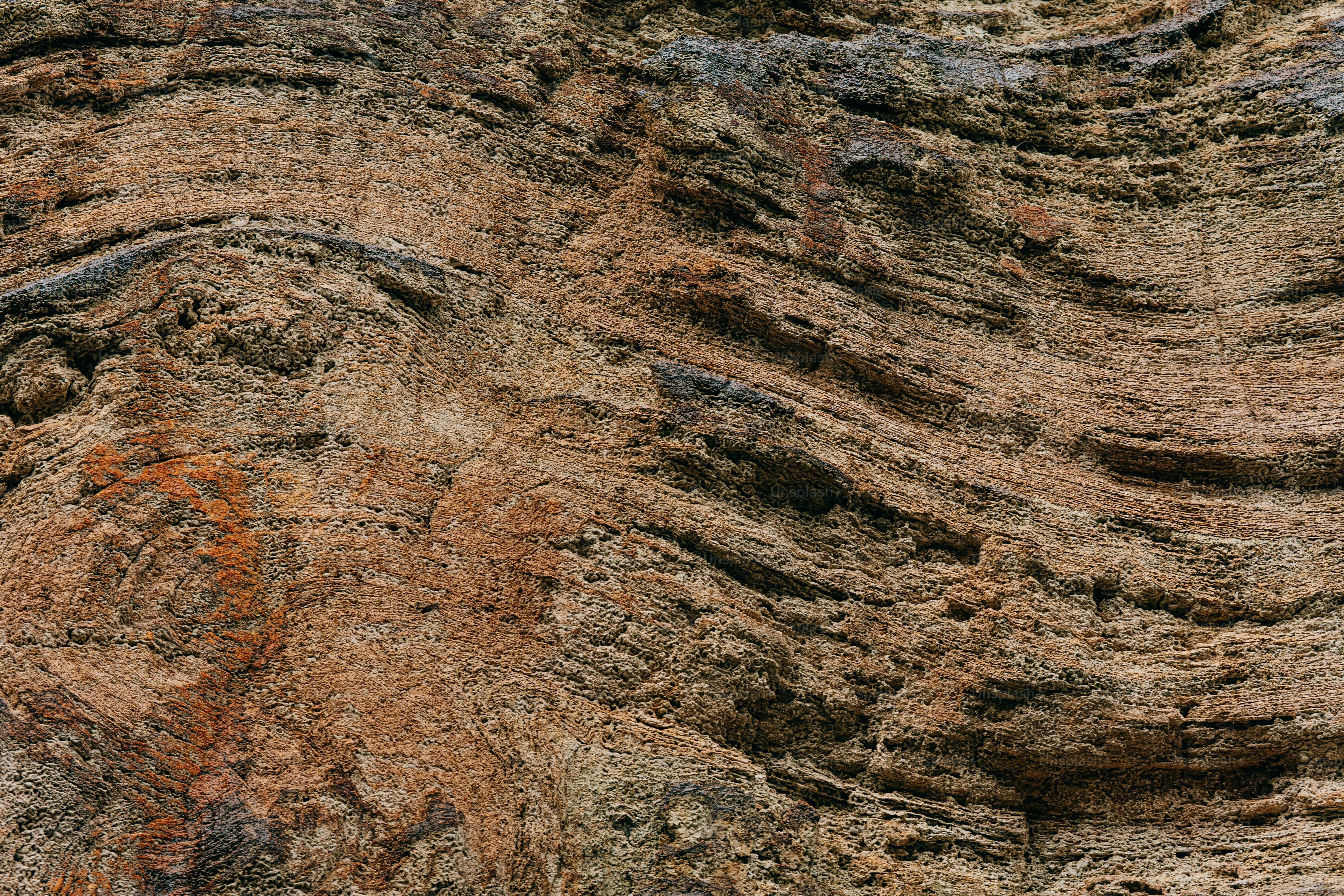 Formasi batuan berlapis coklat dan kemerahan dengan tekstur geologi yang terlihat.