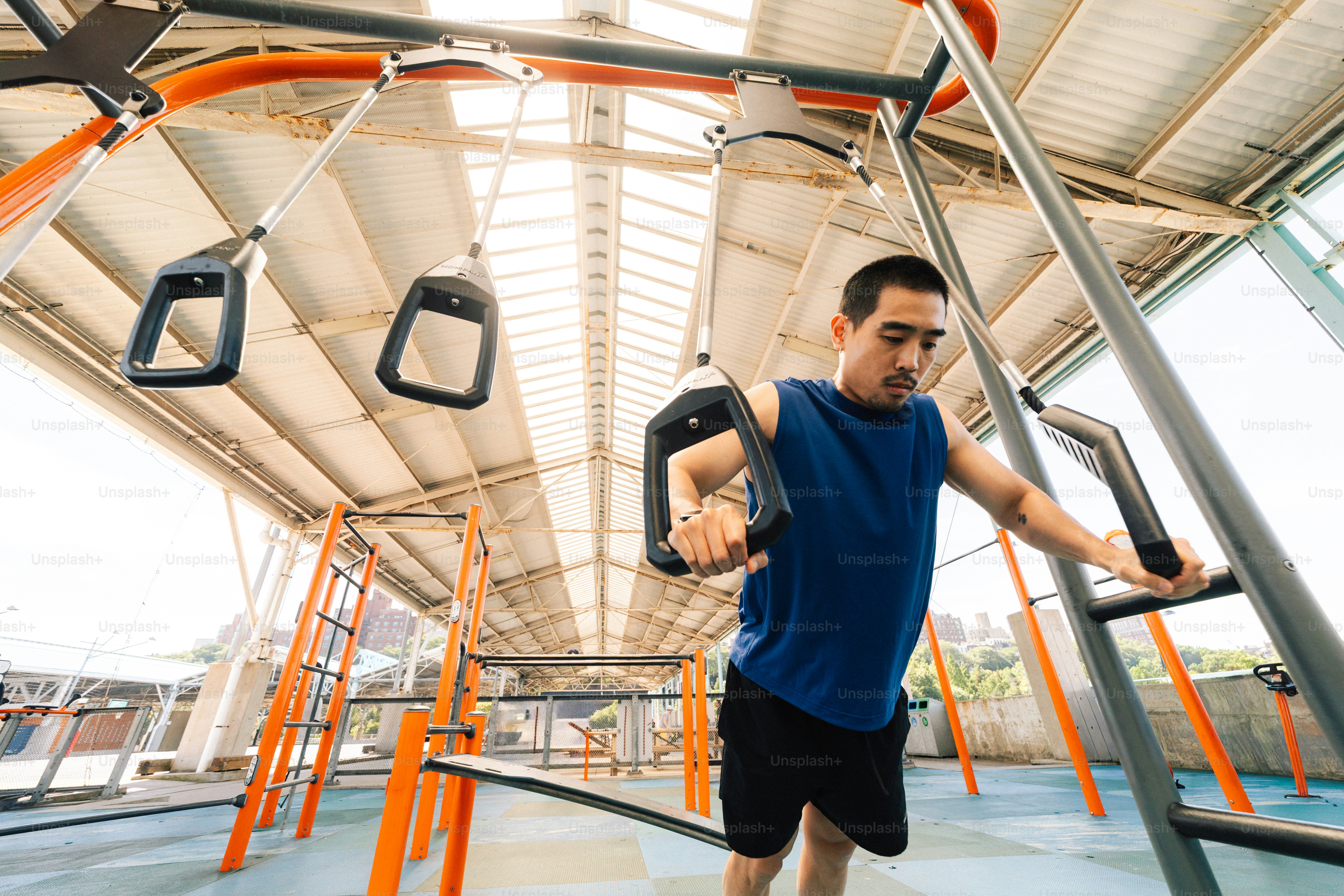 Pria atletis berlatih dengan cincin suspensi di gym luar ruangan.